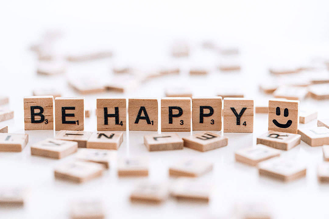Positive 桌布 壁紙 — 木製 Scrabble 字母磚在亮白色表面上拼出 'BE HAPPY'，旁邊有一個笑臉磚。