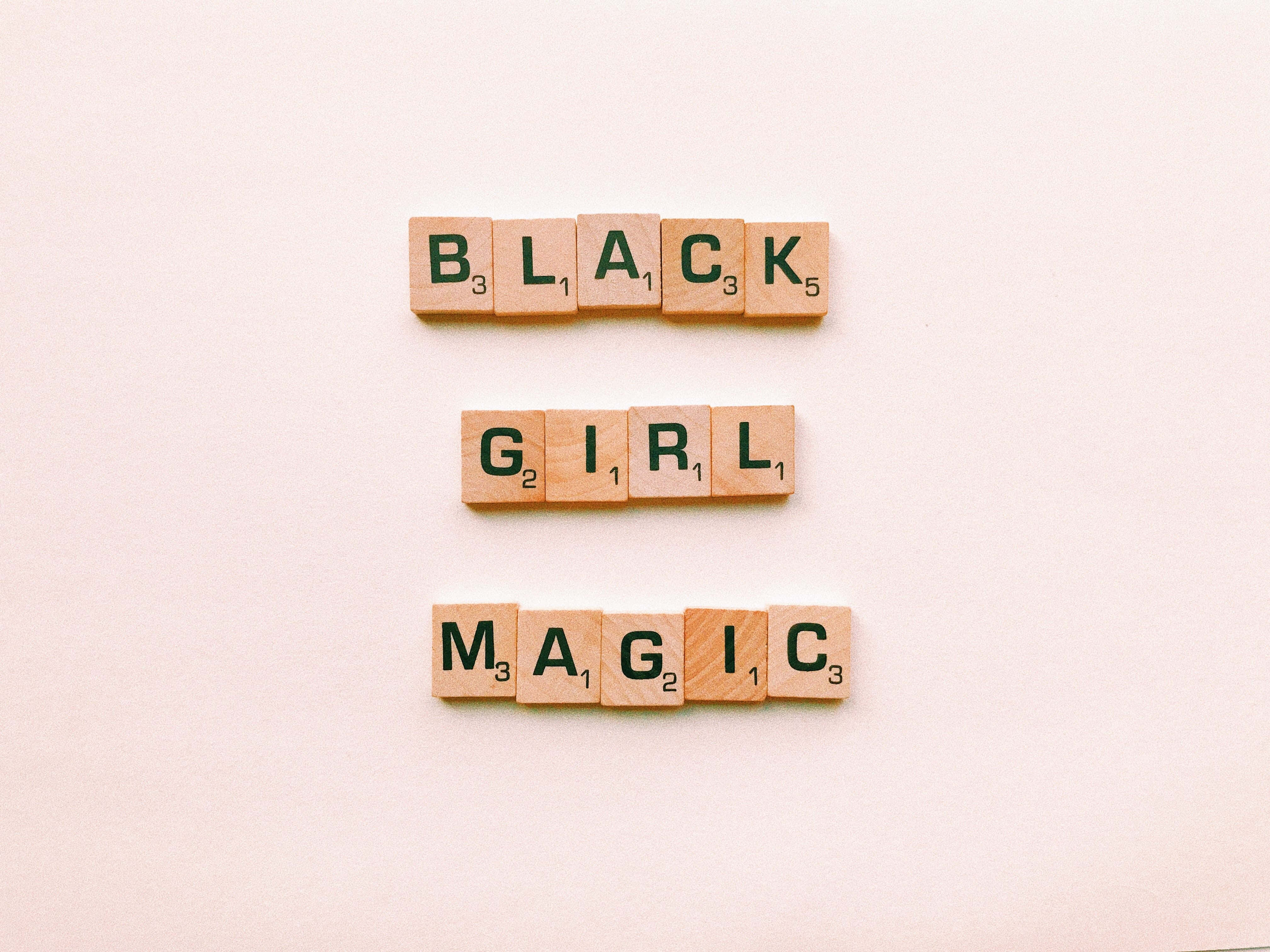 Black Girl Magic 桌布 壁紙 — 木製 Scrabble 字母磚在柔軟的米色背景上用綠色字母拼出「BLACK GIRL MAGIC」。