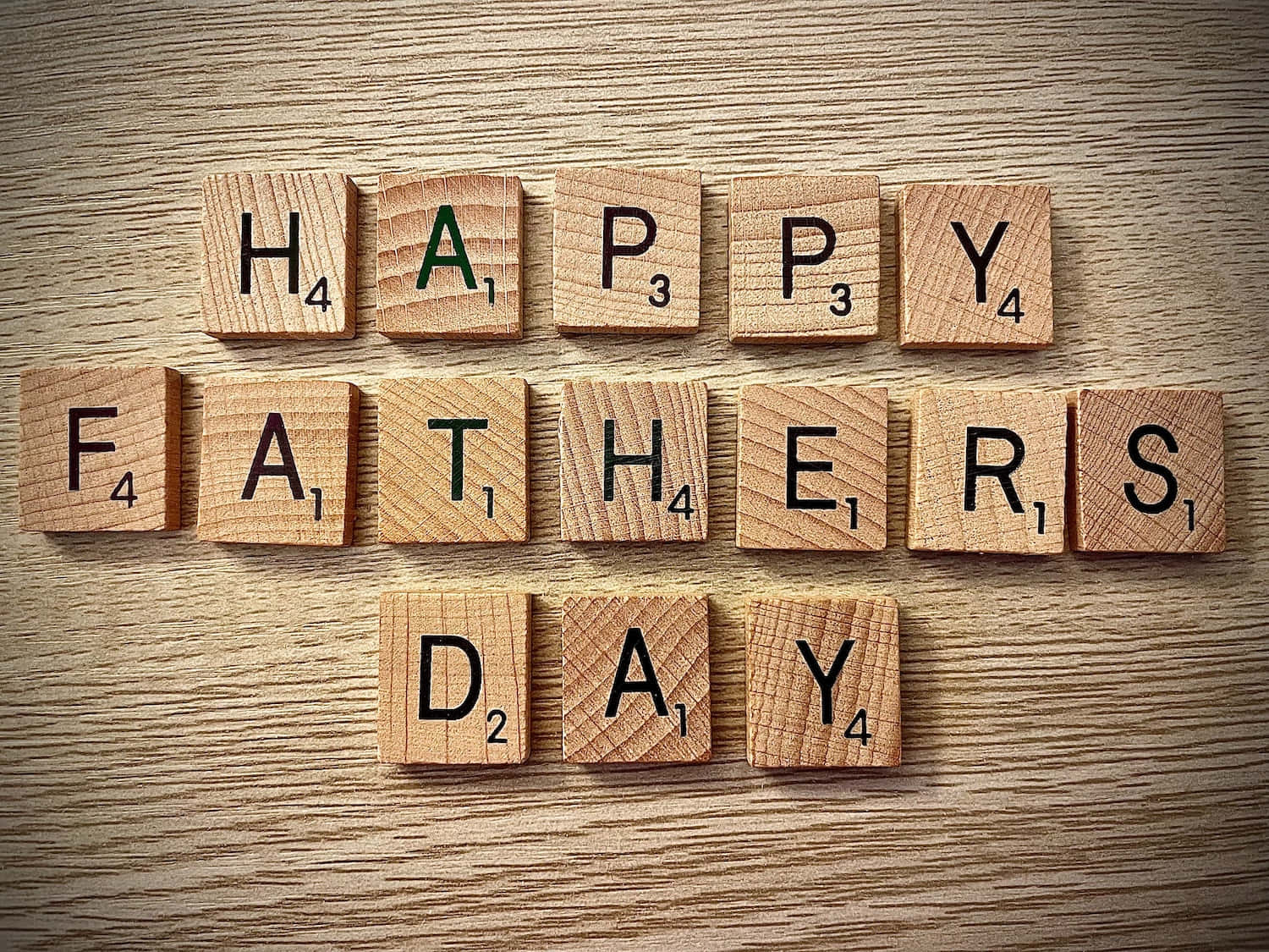 Fathers Day 桌布 壁紙 — 木製 Scrabble 字母磚在帶有天然木紋的紋理木質表面上拼出「HAPPY FATHERS DAY」。