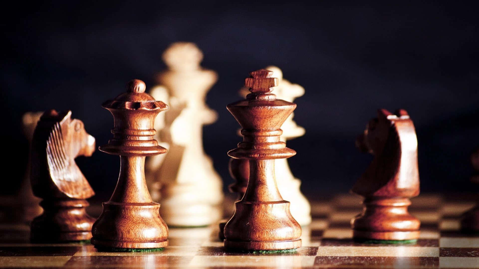 西洋棋 桌布 壁紙 — 木製國際象棋棋子於棋盤上的特寫，帶有戲劇性燈光和淺景深。