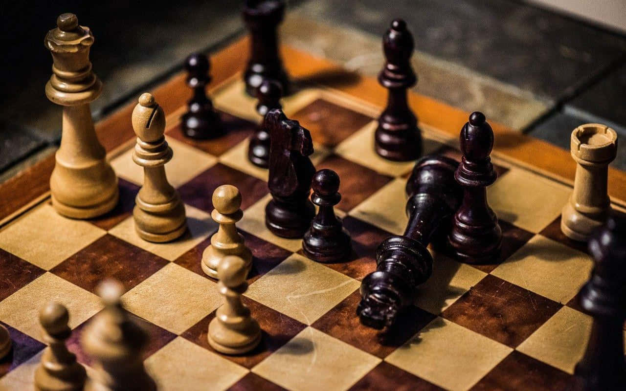 西洋棋 桌布 壁紙 — 木製國際象棋棋子於棋盤上的特寫，有倒下的棋子顯示一場激烈的比賽正在進行。