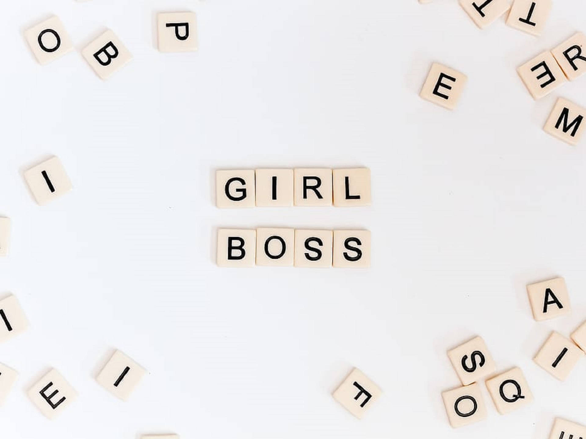boss 桌布 壁紙 — 木製字母拼出「GIRL BOSS」，置於潔白表面中央，周圍散落字母。