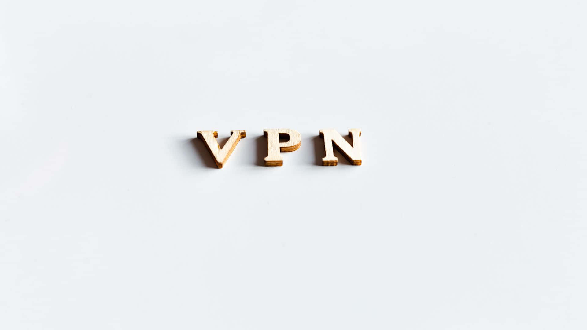 標誌 桌布 壁紙 — 木製字母拼出 VPN，居中放置在純白色表面上，帶有柔和陰影。
