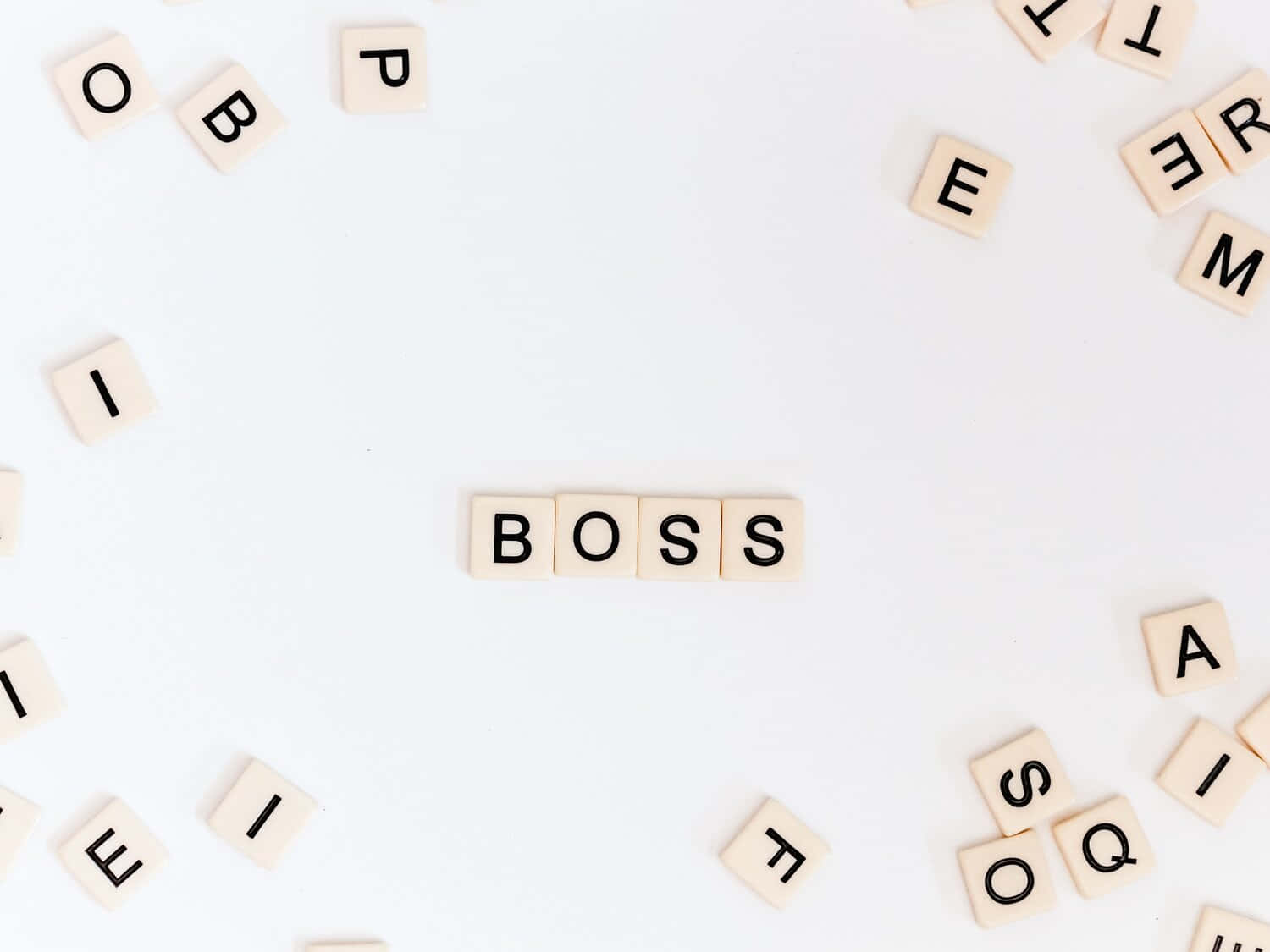 Word 桌布 壁紙 — 木製字母瓷磚在白色表面上居中拼出「BOSS」，周圍散落著字母瓷磚。
