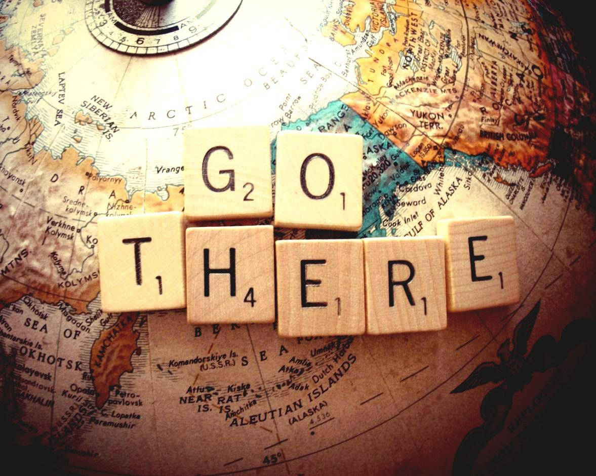 Cool Vintage 桌布 壁紙 — 木製拼字磚拼出「GO THERE」，放在一個顯示北極和阿拉斯加地區的復古地球儀上。