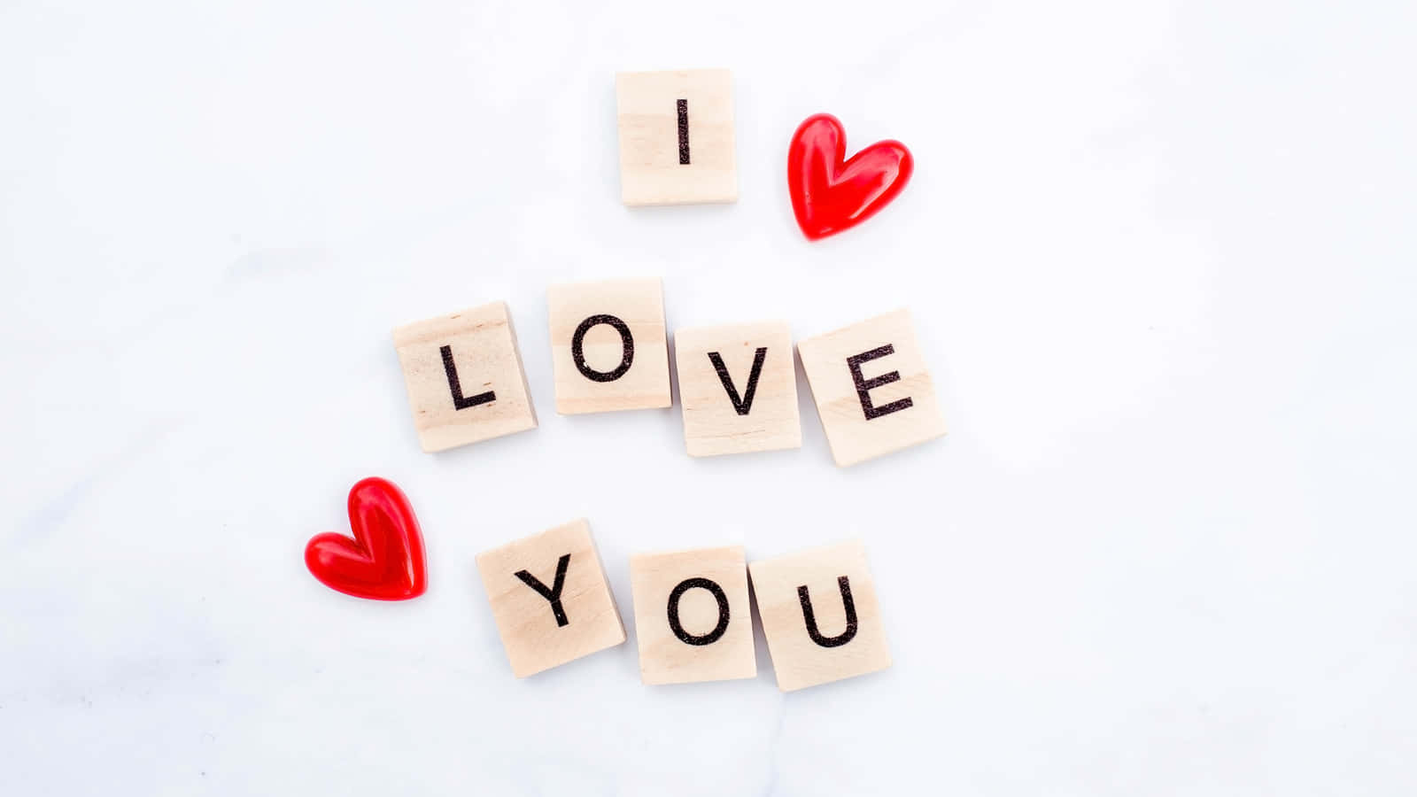 我愛你 桌布 壁紙 — 木製方塊在潔白的大理石表面上拼出「I LOVE YOU」，並帶有紅色心形吊飾。