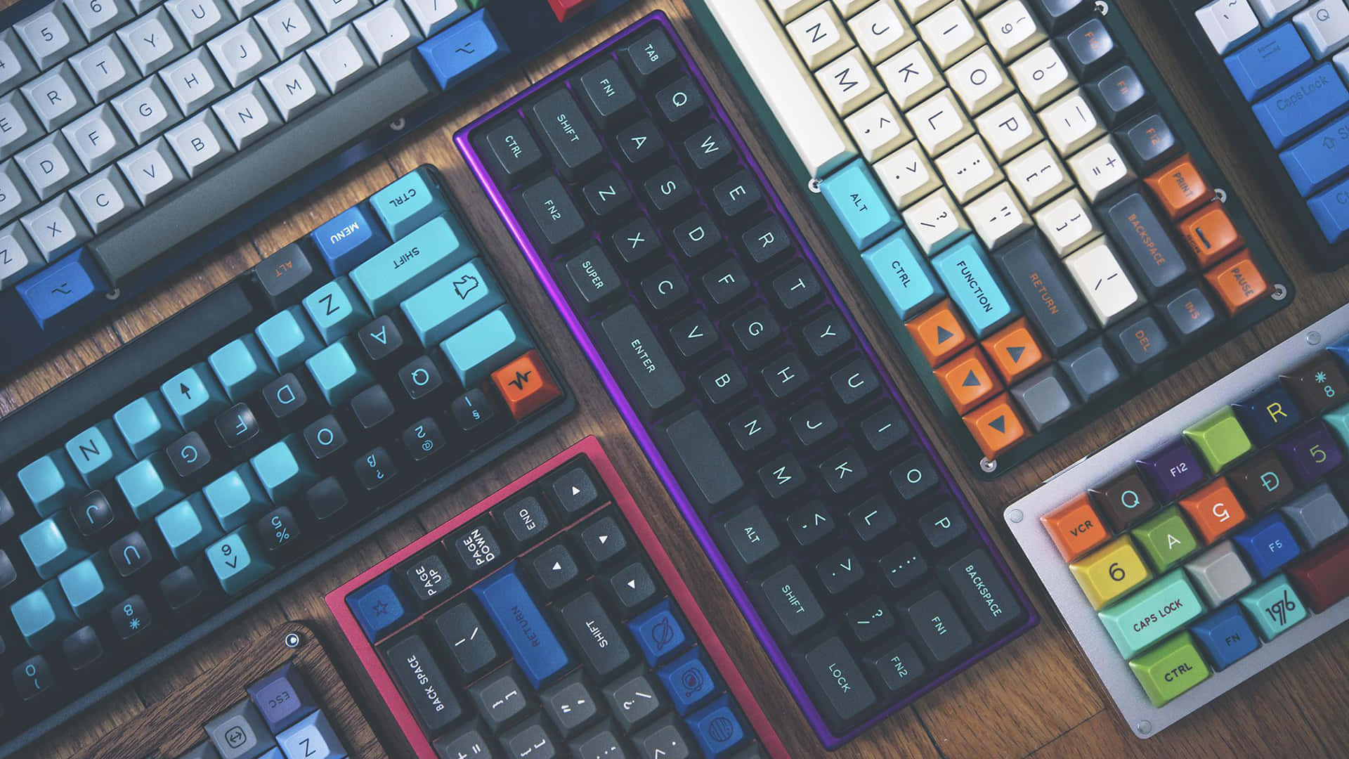 Cute Keyboard 桌布 壁紙 — 木製書桌上色彩繽紛的鍵帽的多個自訂機械鍵盤的充滿活力的俯視圖。