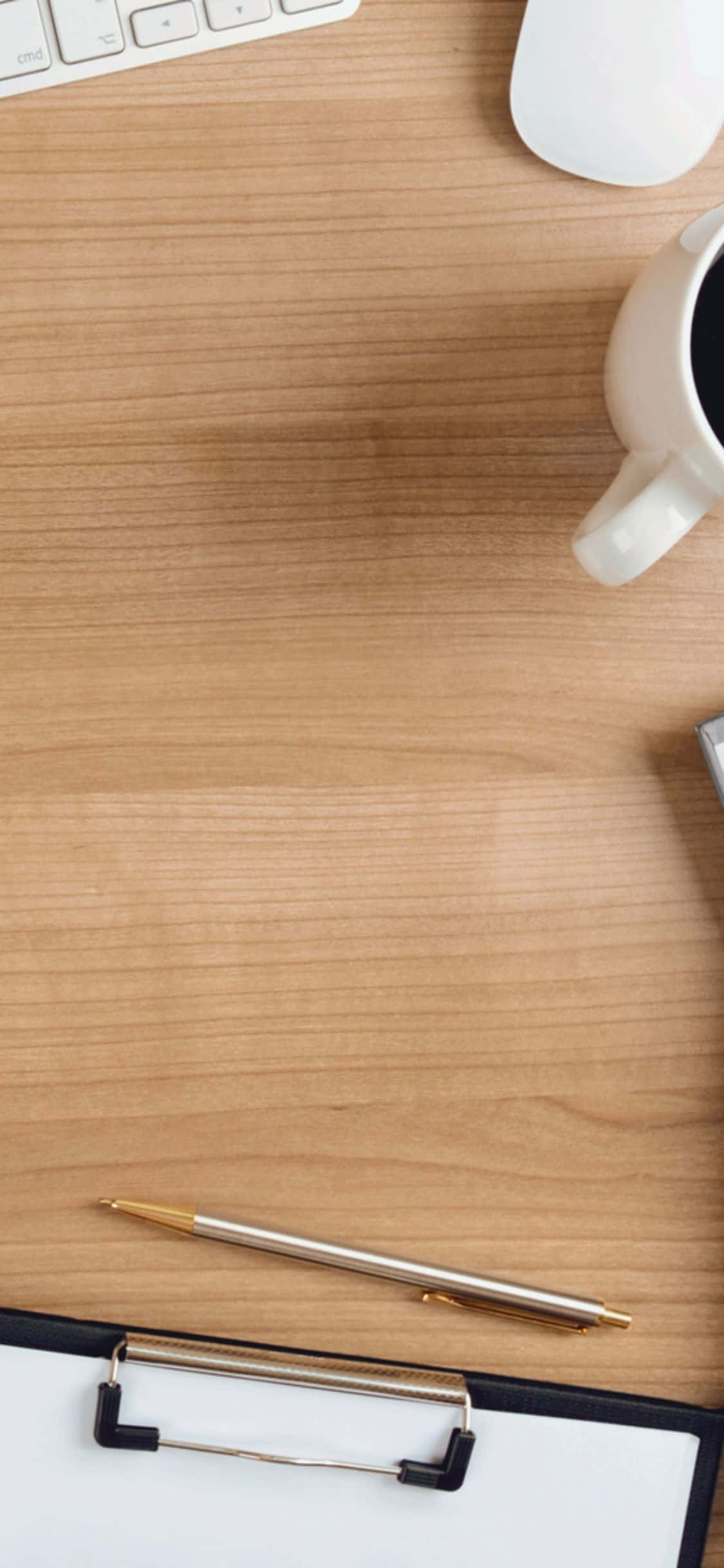 iPhone Xs Desk 桌布 壁紙 — 木製書桌的俯視圖，整齊地擺放著咖啡杯、鍵盤、滑鼠、筆和夾板，方便工作。