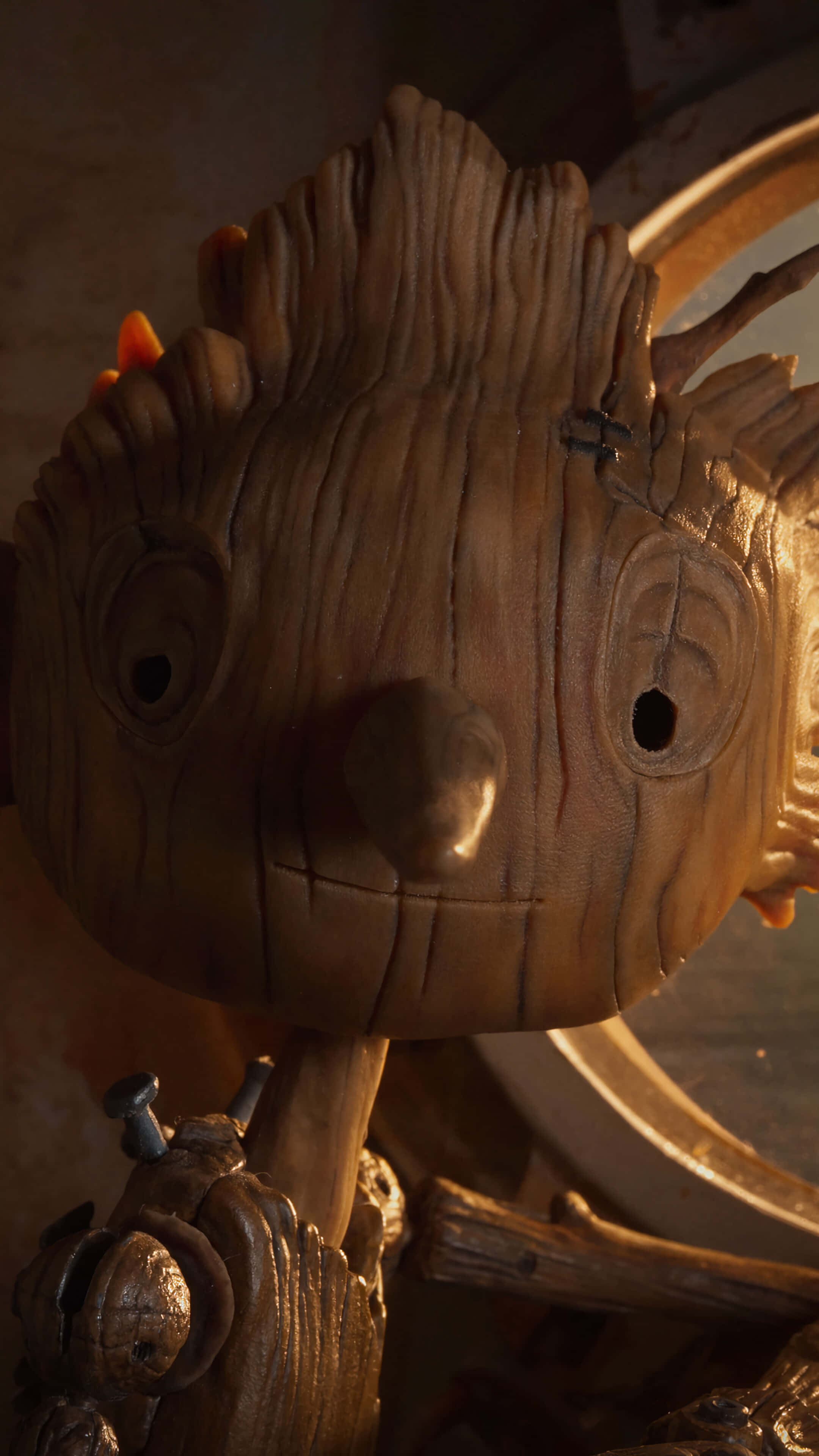Guillermo Del Toro's Pinocchio 桌布 壁紙 — 木製格魯特公仔的特寫，具有紋理樹皮狀皮膚和溫暖燈光，突顯其雕刻的面部特徵。