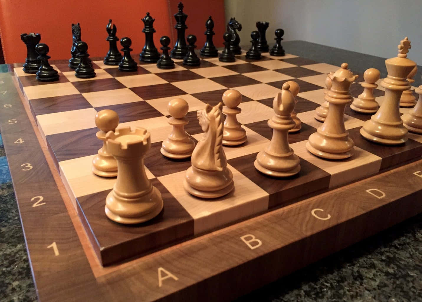 Chessboard 桌布 壁紙 — 木製棋盤的特寫，上面有淺色和深色棋子，排列在檯面上準備對弈。