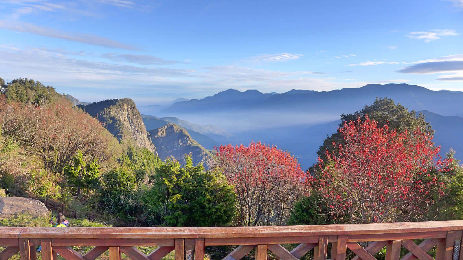 山景 桌布 壁紙 — 木製欄杆框住令人驚嘆的山景，在清澈的藍天下，層巒疊嶂襯托著鮮紅的秋樹。