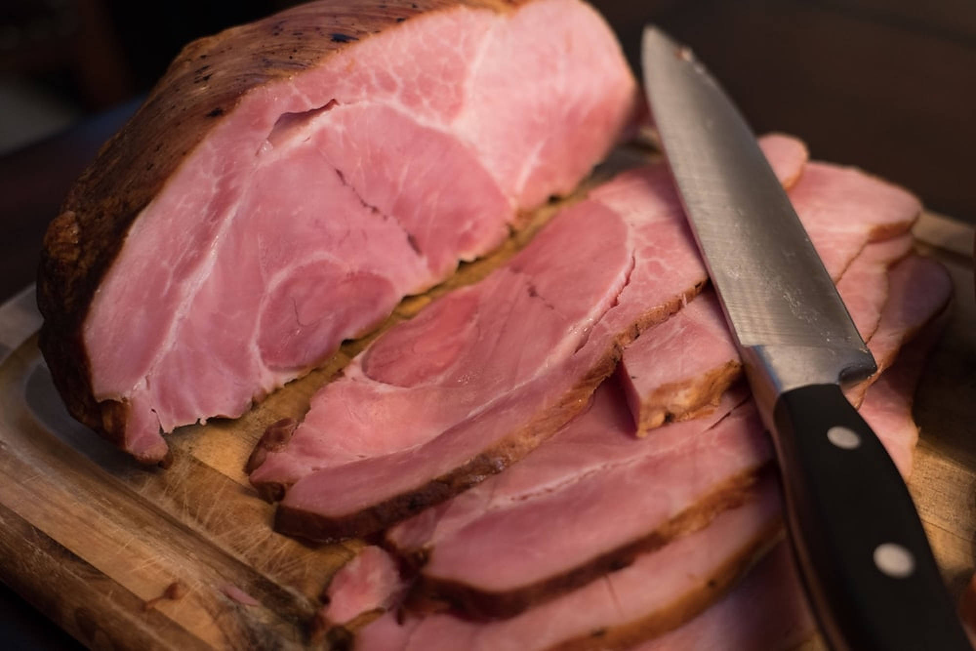 Ham 桌布 壁紙 — 木製砧板上切片火腿的特寫，旁邊放著一把刀。