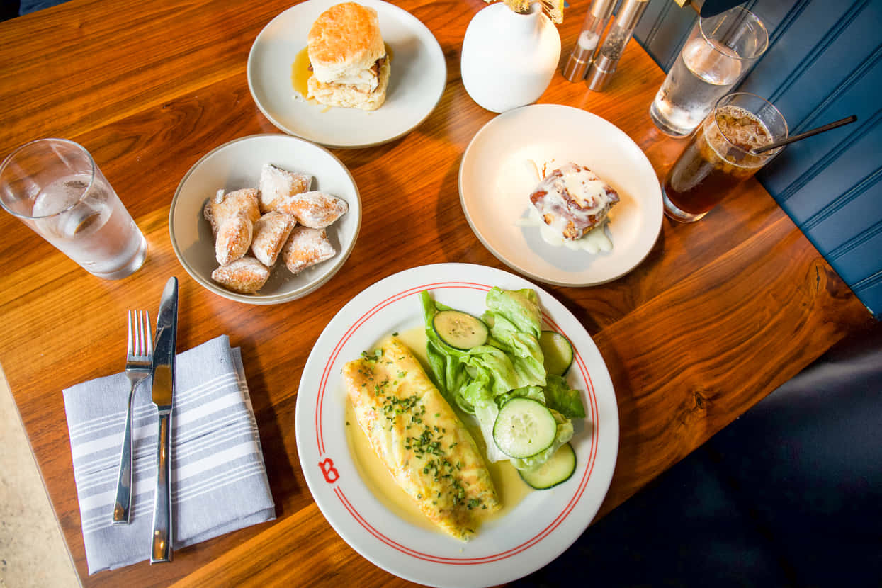 Brunch 桌布 壁紙 — 木製餐桌上擺放早餐盤的俯視圖，包括魚沙拉餅乾和撒粉糕點。