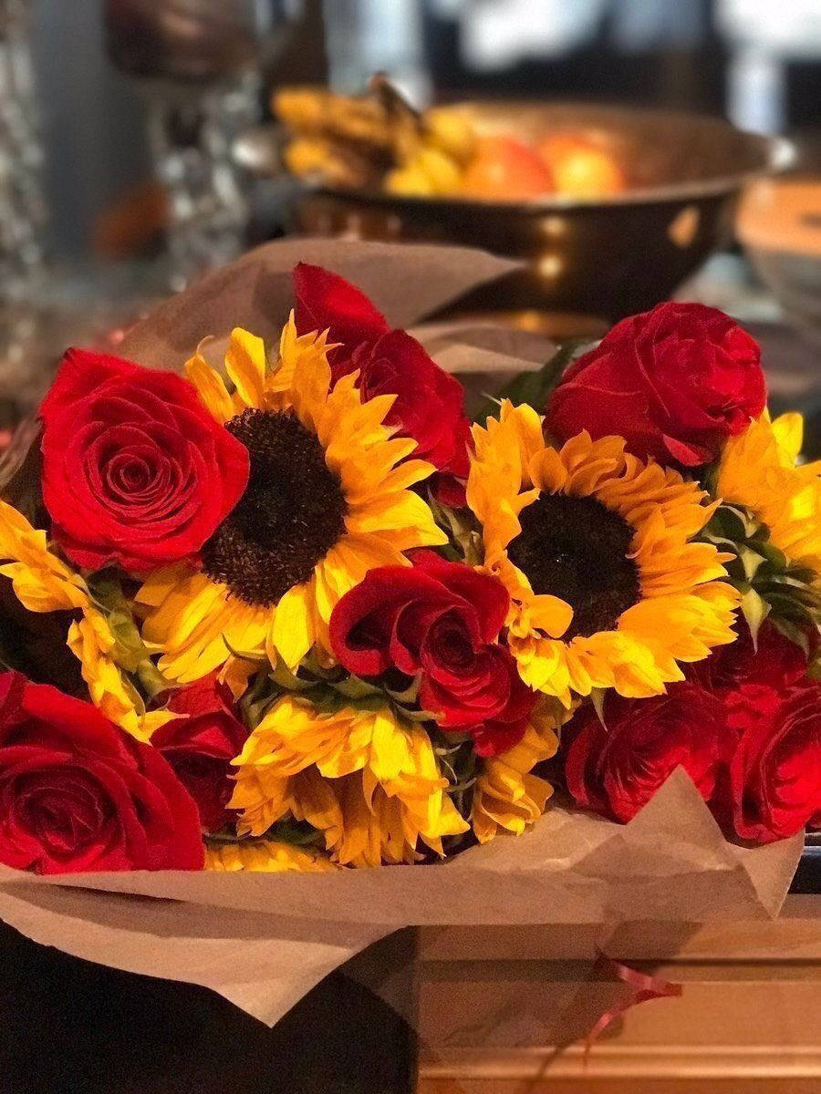 Red Roses 桌布 壁紙 — 木質表面上用牛皮紙包裹的紅玫瑰和黃色向日葵的鮮豔花束。