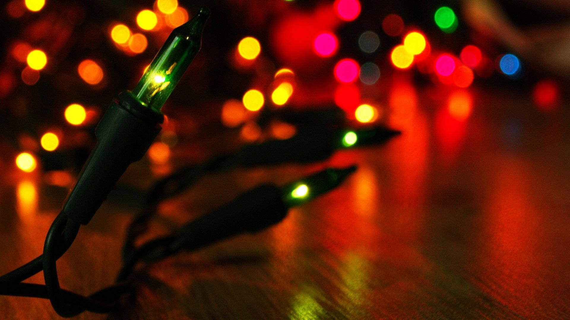 Christmas Lights Aesthetic 桌布 壁紙 — 木質表面上發光綠色串燈的特寫，帶有模糊彩色散景。