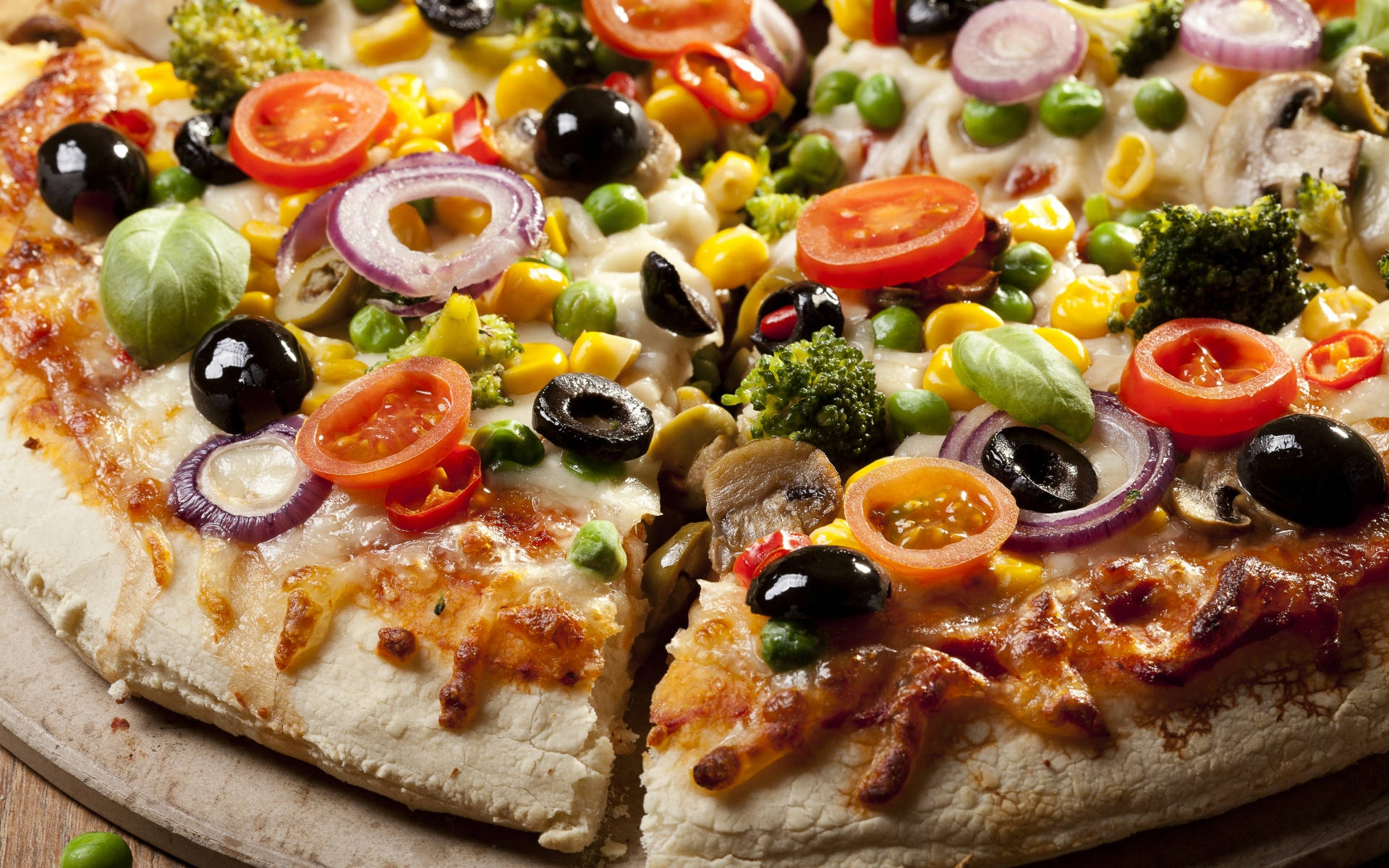 Pizza 桌布 壁紙 — 木質表面上的新鮮出爐蔬菜披薩，上面鋪滿鮮豔的櫻桃番茄、橄欖和西蘭花的特寫。