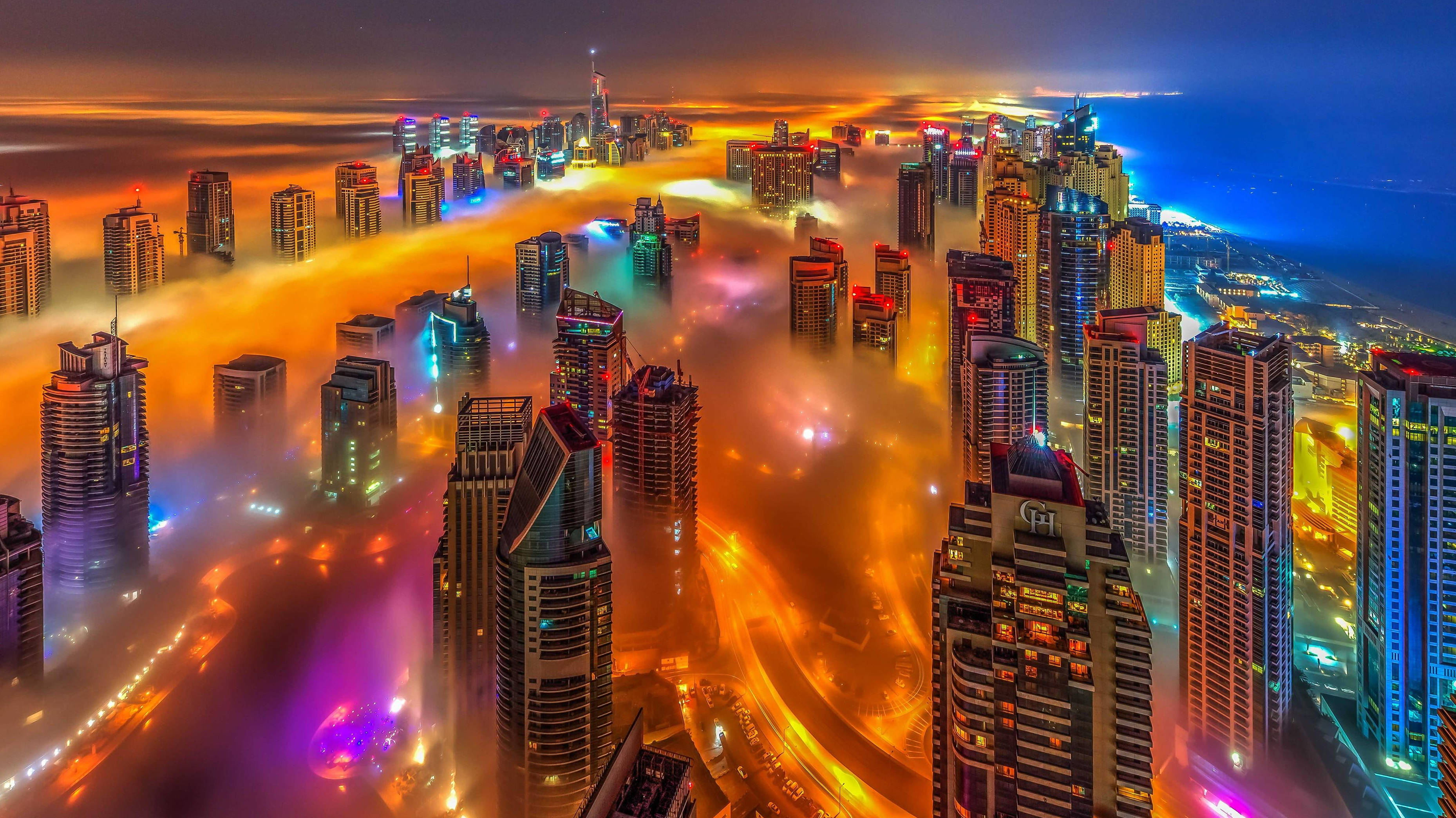 Arab 桌布 壁紙 — 未來城市摩天大樓在暮色中穿透發光的橙色和紫色雲層的鳥瞰圖。