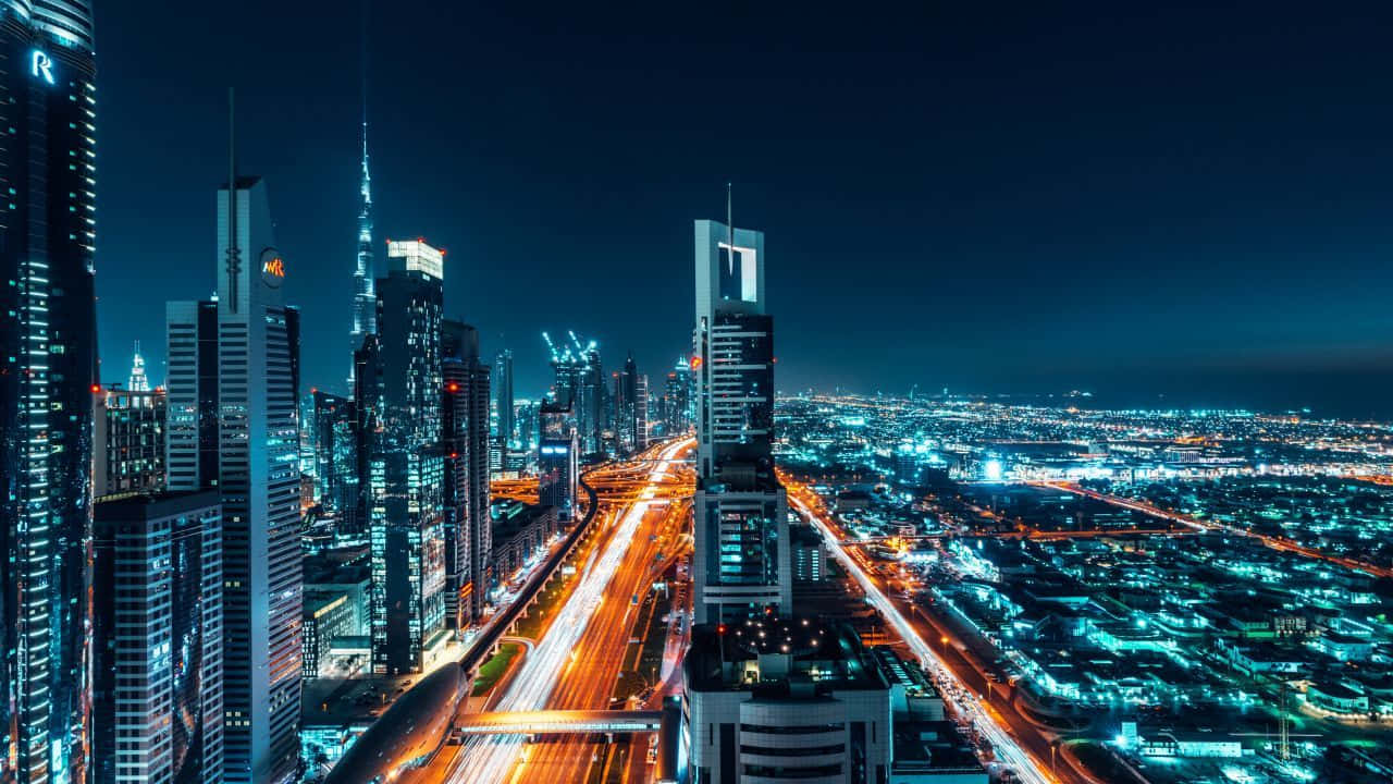 杜拜 桌布 壁紙 — 未來城市景觀的空中夜景，閃爍的摩天大樓和流動的交通燈光。