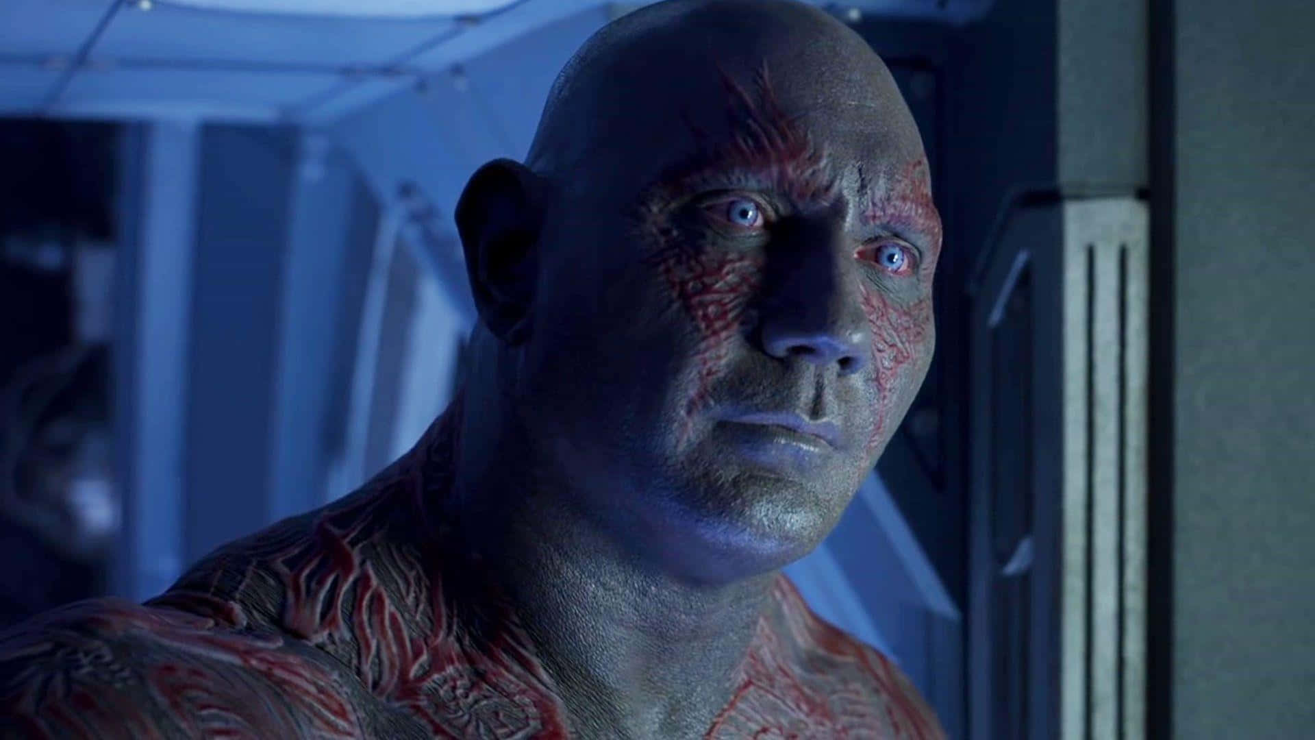 Drax 桌布 壁紙 — 未來走廊中藍色燈光下光頭男子帶紅色部落標記的特寫。
