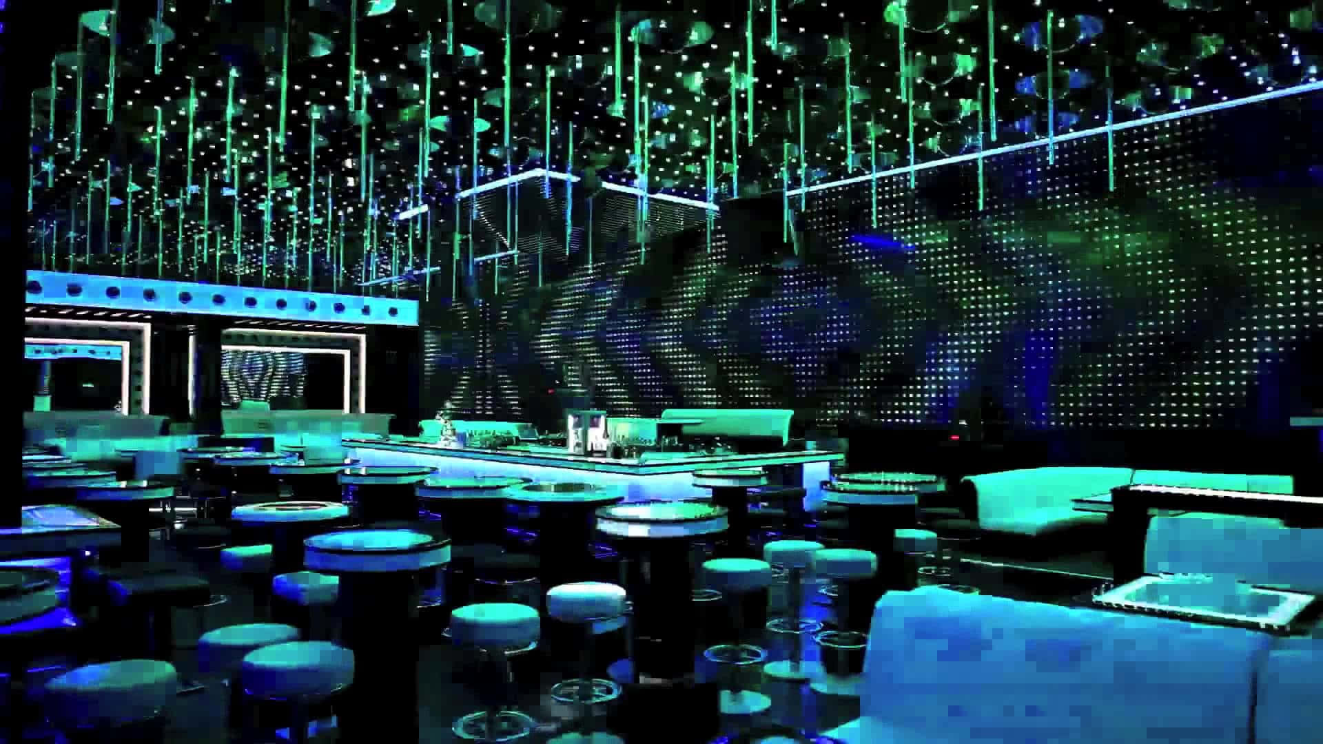 Nightclub 桌布 壁紙 — 未來風格的夜總會，閃爍的綠色和藍色燈光從星空天花板垂下，照亮時尚的桌子和凳子。