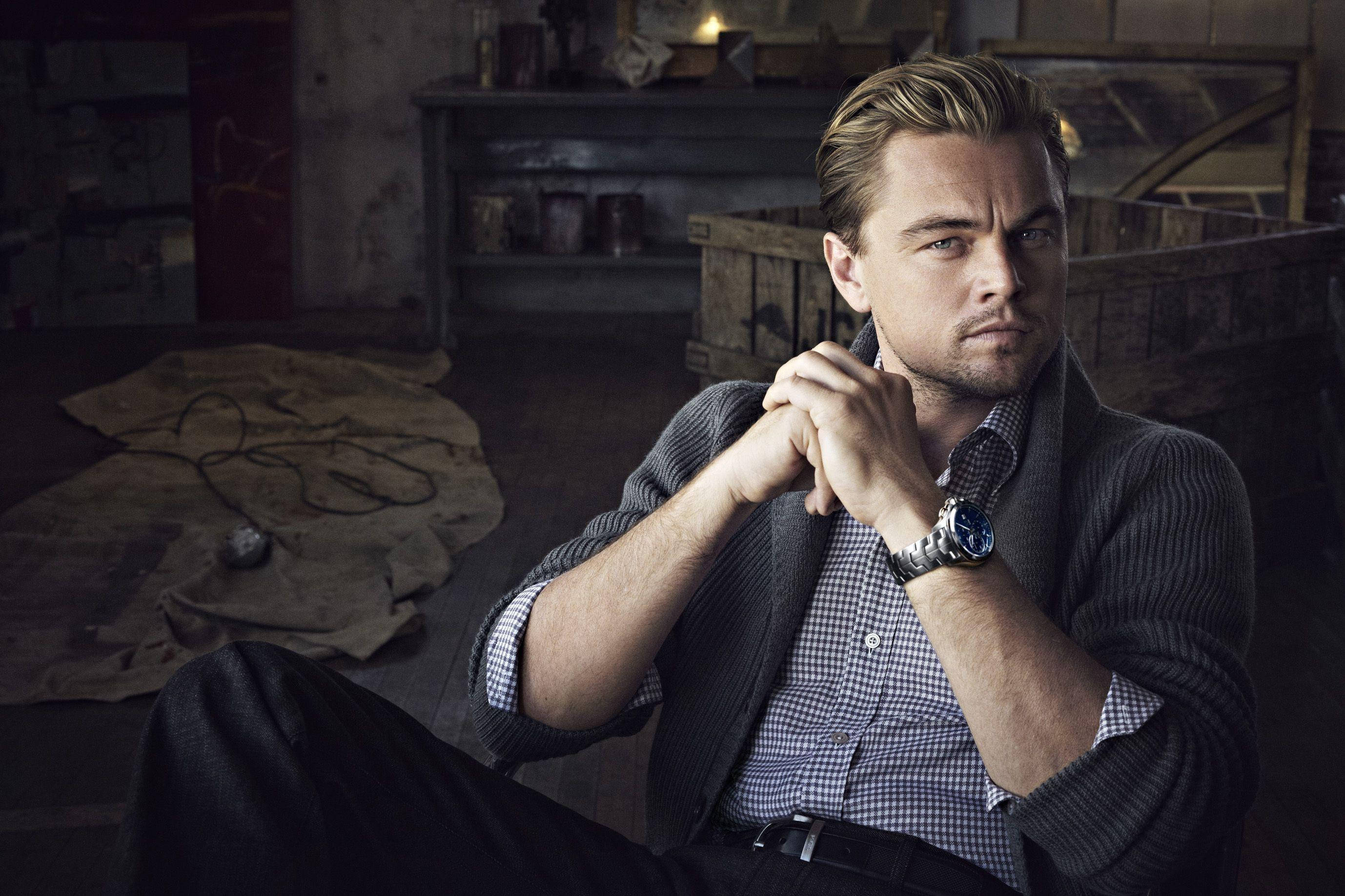 Dicaprio 桌布 壁紙 — 李奧納多·狄卡皮歐在光線昏暗的鄉村風格房間中沉思，雙手緊握，神情嚴肅。
