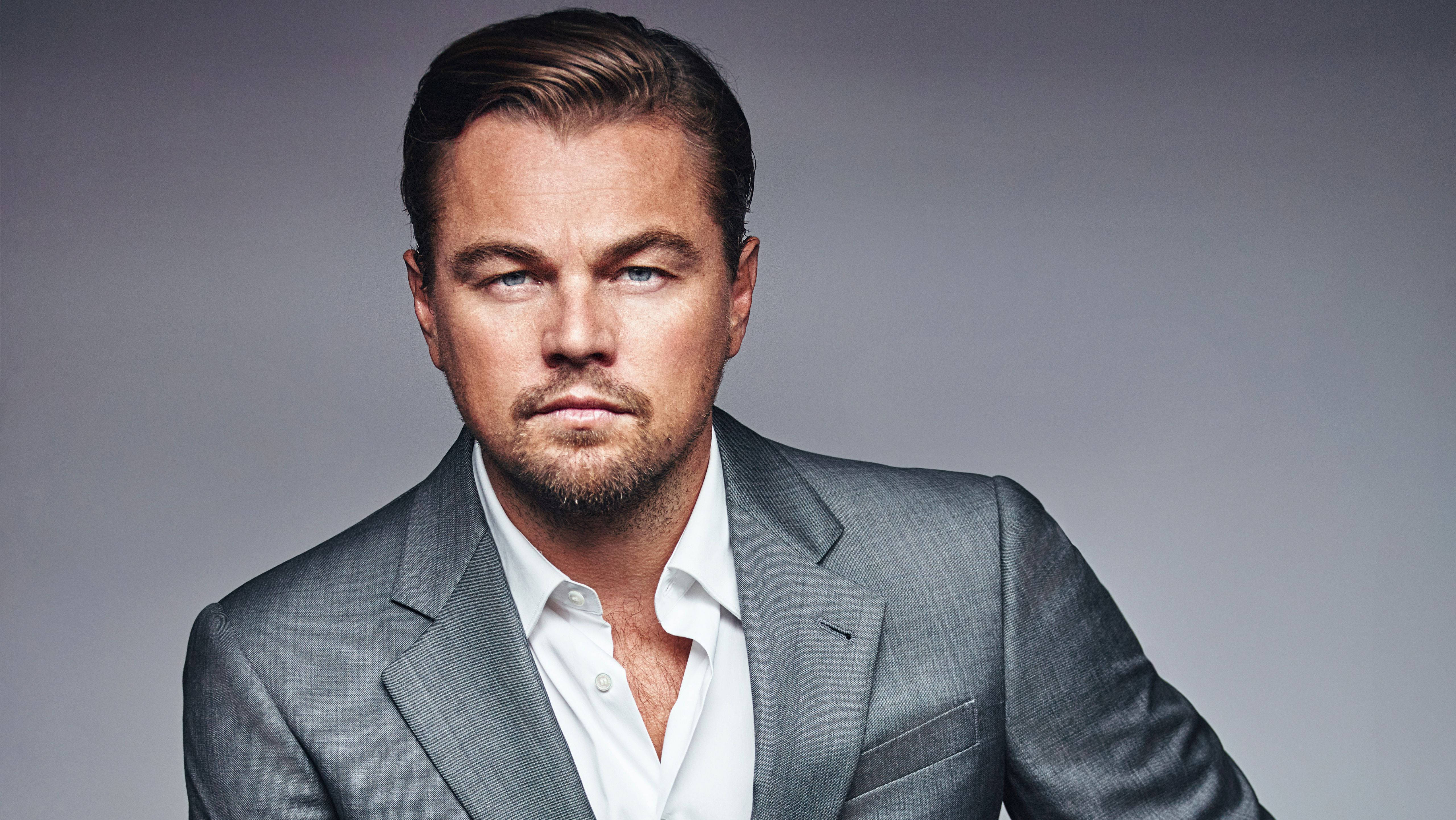 Dicaprio 桌布 壁紙 — 李奧納多·狄卡皮歐在柔和的灰色工作室背景下，穿著尖銳的灰色西裝，專注地凝視。