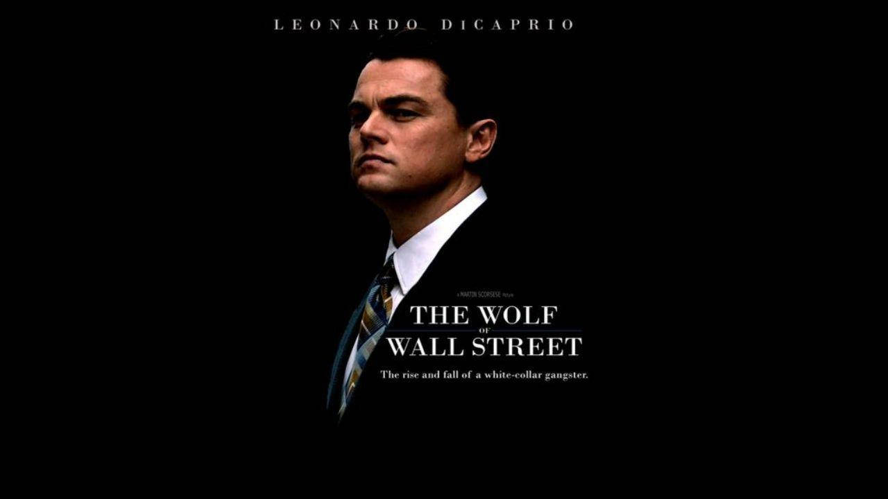 Wolf Of Wall Street 桌布 壁紙 — 李奧納多·狄卡皮歐身穿筆挺西裝，在純黑背景上凝視著電影標題文字。