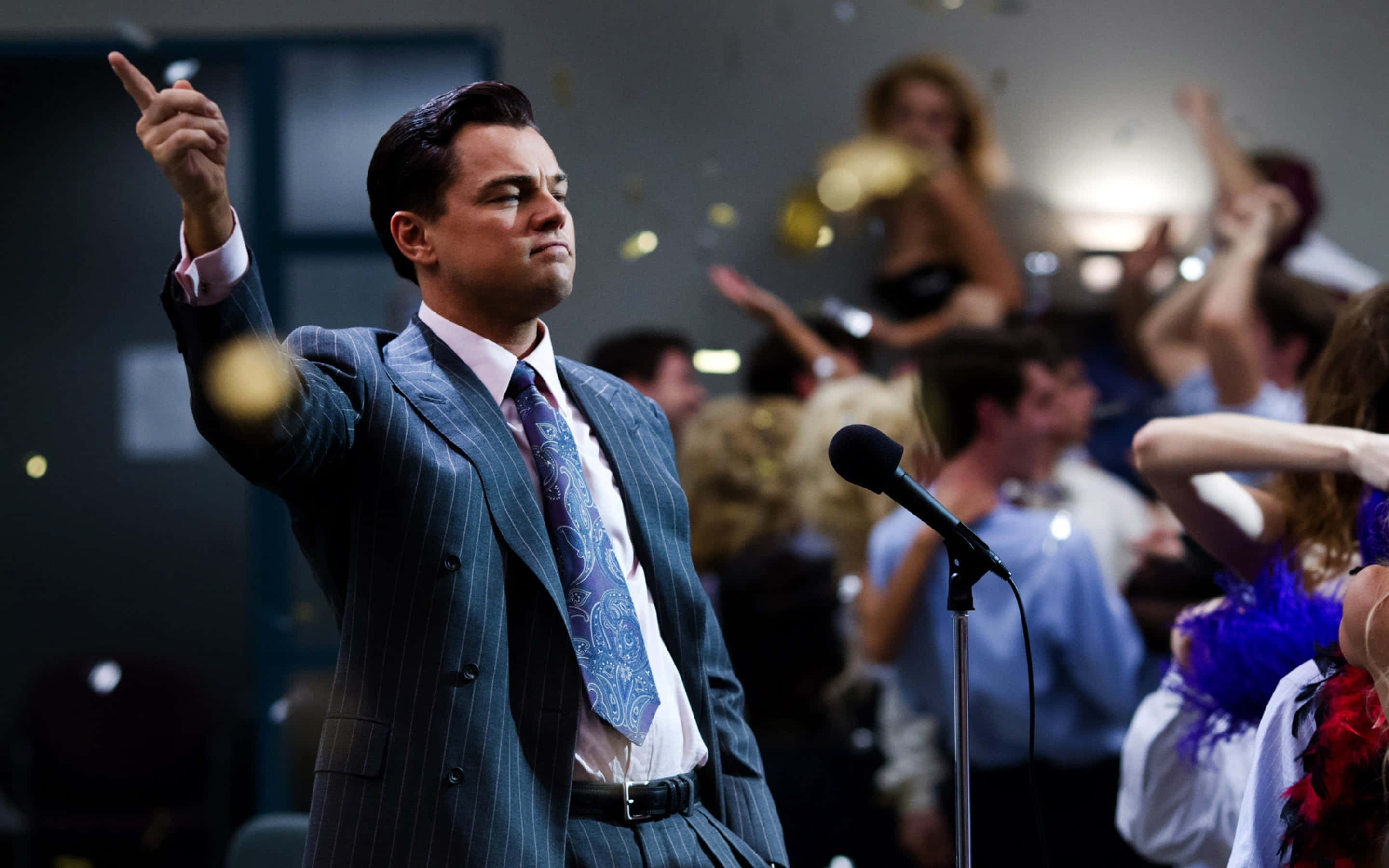 Wolf Of Wall Street 桌布 壁紙 — 李奧納多·狄卡皮歐身穿細條紋西裝向上指，金色紙屑在熱鬧派對中飄落，賓客歡呼。