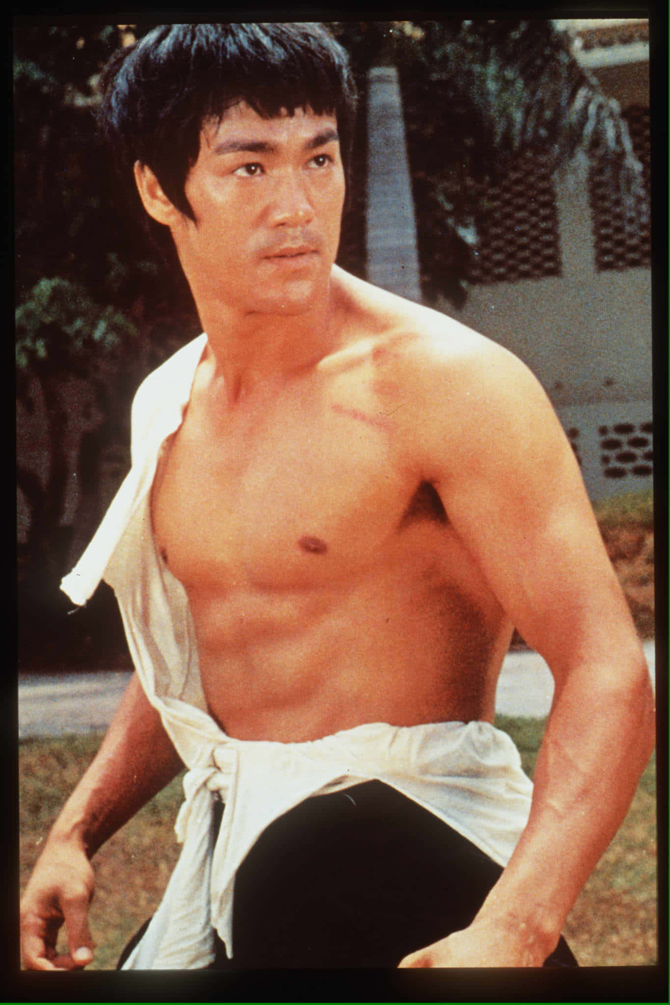 李小龍 桌布 壁紙 — 李小龍以強勁武術姿勢，赤裸上身，白色長袍繫在腰間，戶外拍攝。