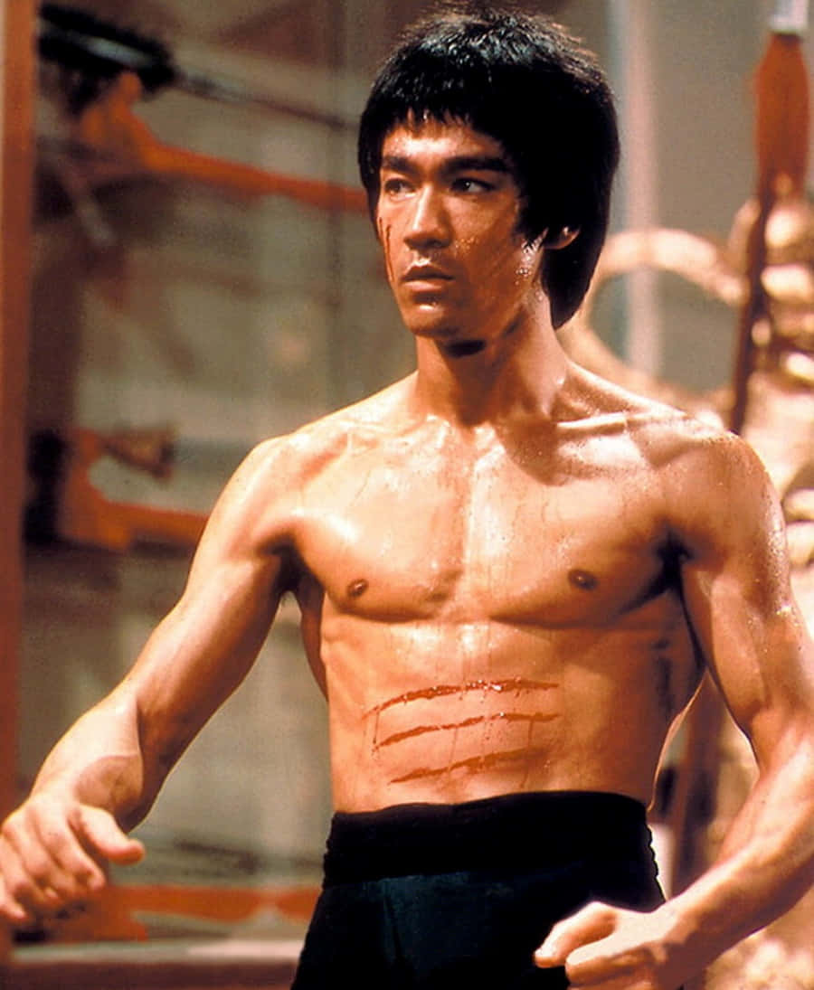 李小龍 桌布 壁紙 — 李小龍在武術道場赤膊站立，汗水在他肌肉發達的軀幹上閃閃發光，腹部有三道紅色劃痕。