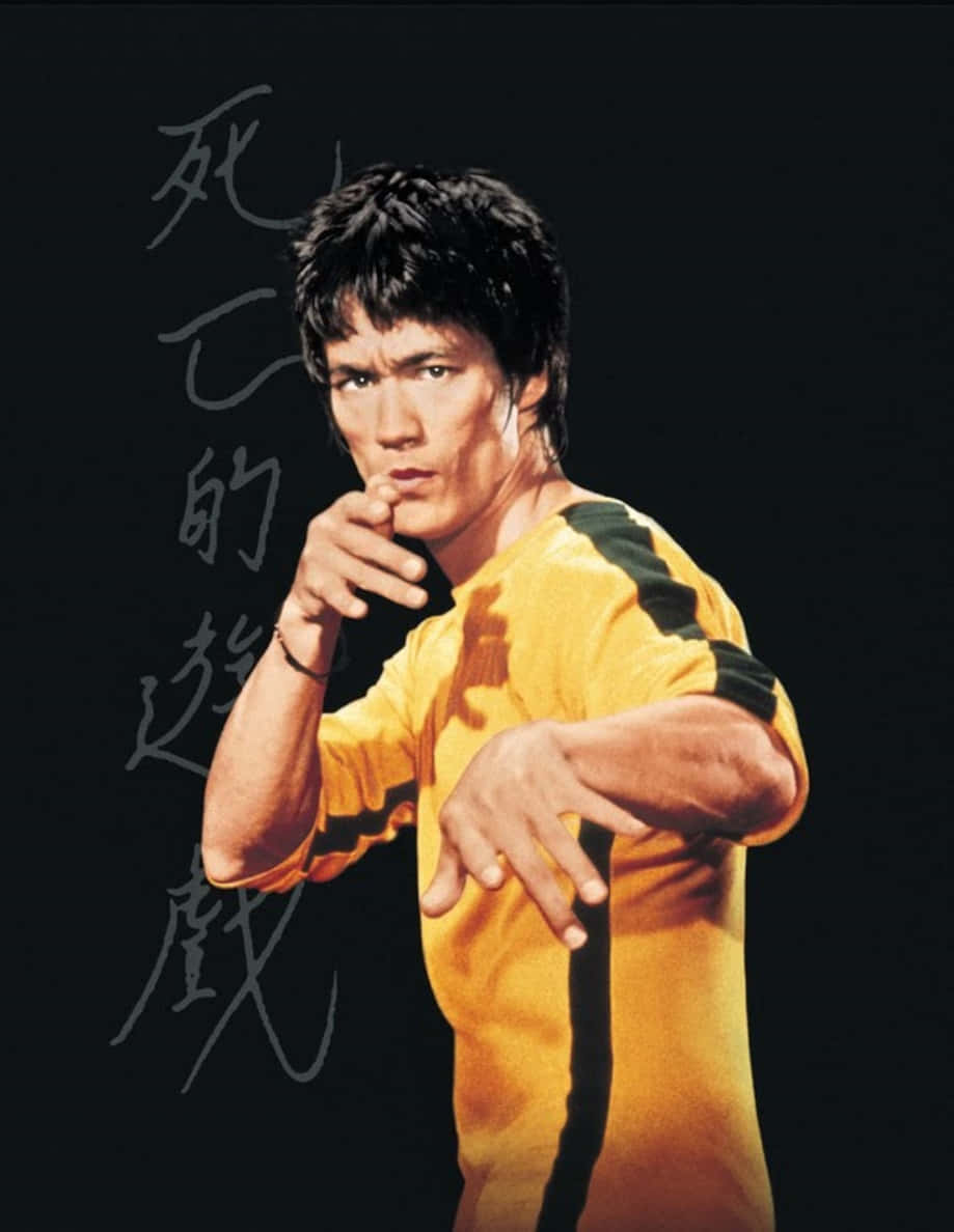 李小龍 桌布 壁紙 — 李小龍身穿標誌性的黃黑武術服，在黑色背景上以中國書法襯托，擺出強而有力的姿勢。