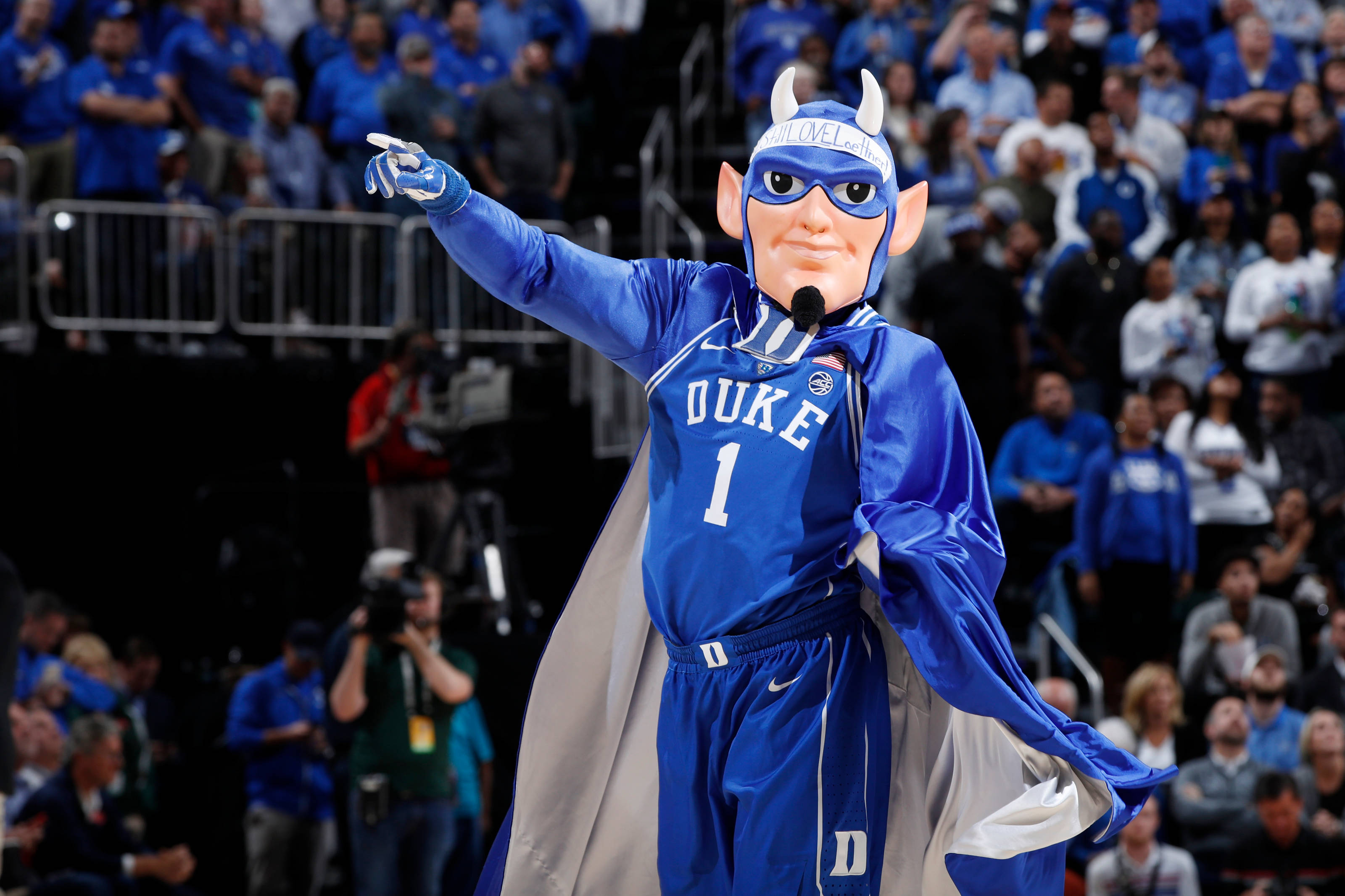 Duke Blue Devils 桌布 壁紙 — 杜克大學的藍魔鬼吉祥物穿著籃球制服，在比賽中充滿活力地指向人群。