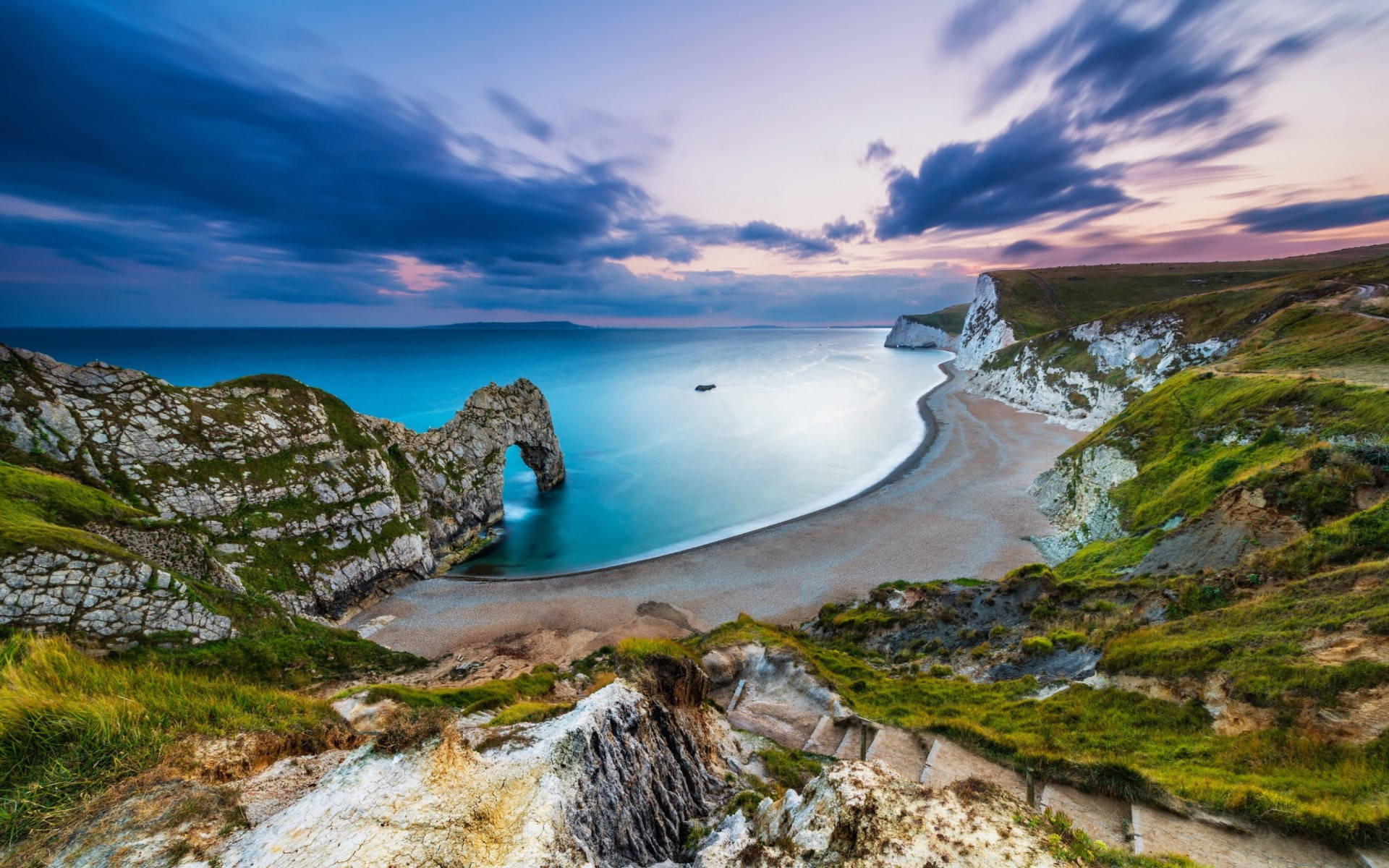 England 桌布 壁紙 — 杜德爾門天然石灰岩拱門框住了暮色中寧靜的碧綠大海，伴隨著戲劇性的雲彩和長滿青草的懸崖。
