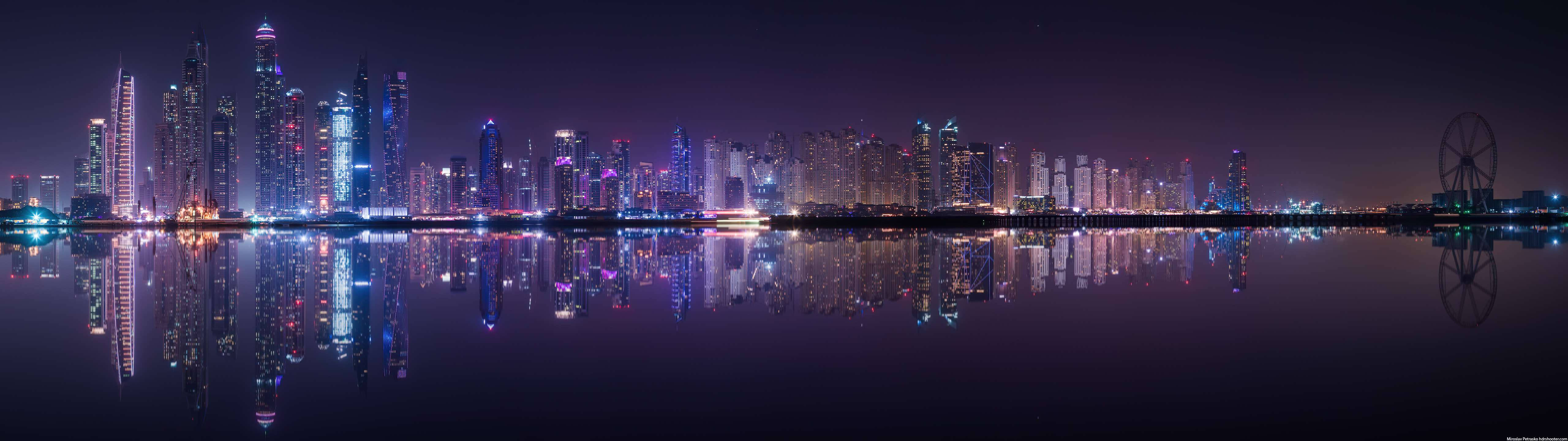 lights 桌布 壁紙 — 杜拜令人目眩的夜景，摩天大樓在霓虹燈光中閃爍，完美倒映在平靜的水面上。