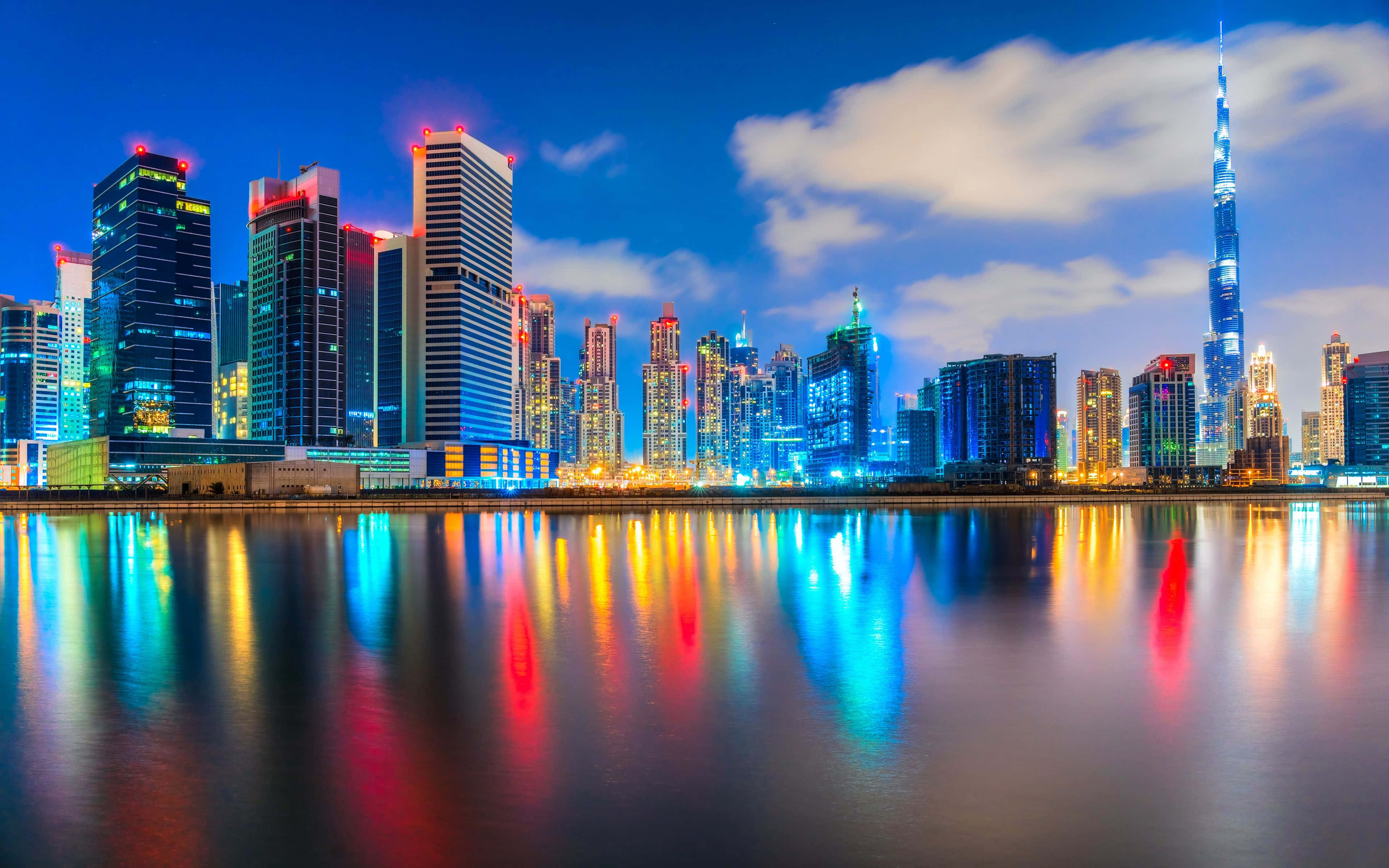 Uae 桌布 壁紙 — 杜拜令人目眩神迷的夜景，摩天大樓在平靜的水面上反射出鮮豔的霓虹燈光。