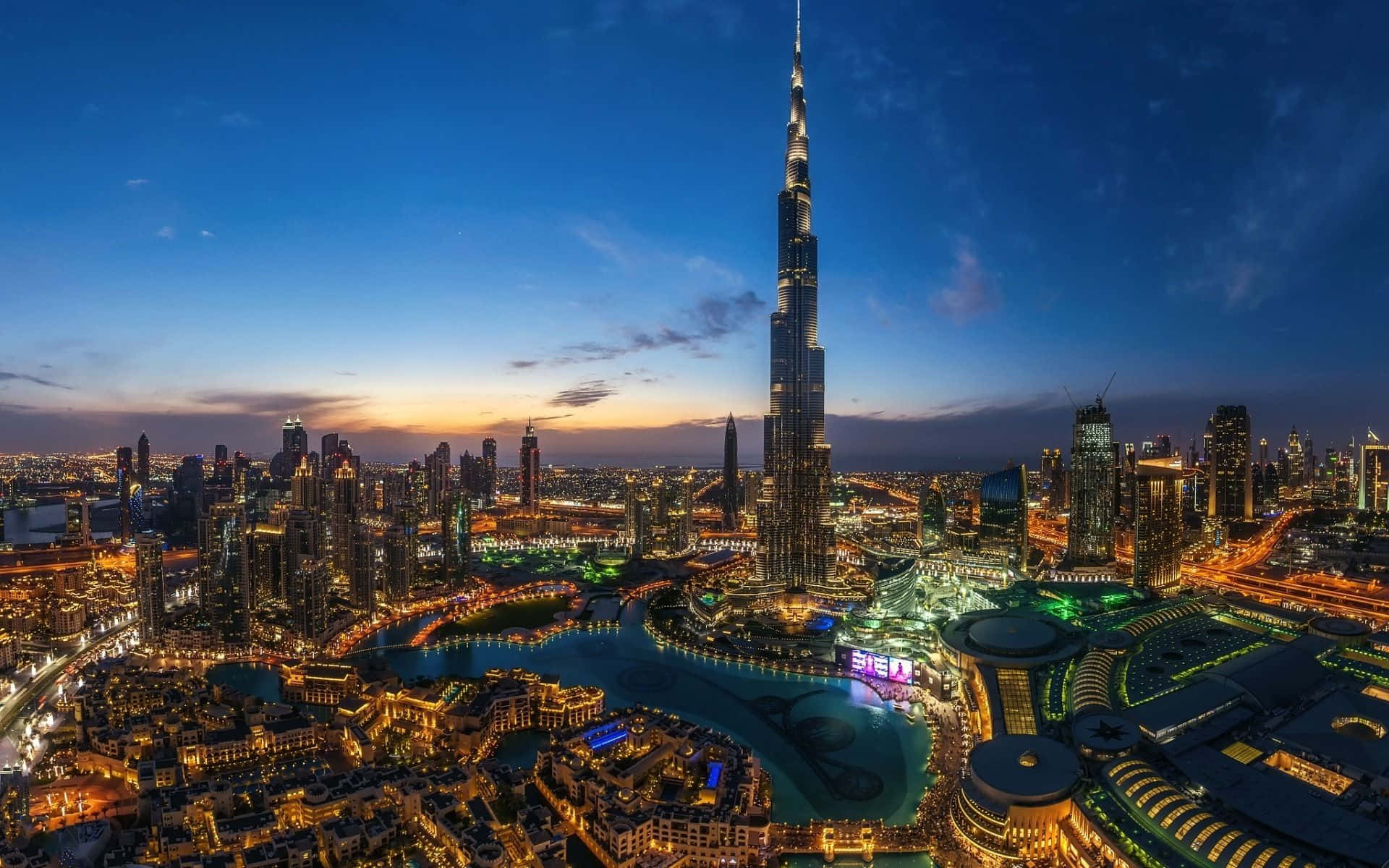 Uae 桌布 壁紙 — 杜拜天際線在黃昏時的鳥瞰圖，哈里發塔聳立於燈火通明的摩天大樓和海濱之上。