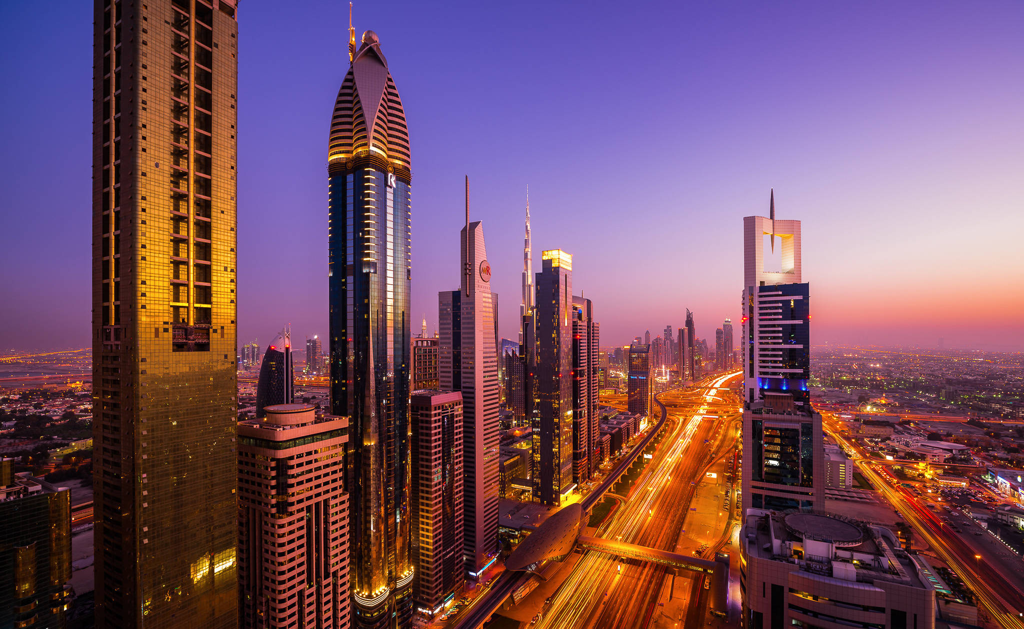 Arab 桌布 壁紙 — 杜拜天際線在黃昏時的鳥瞰圖，有燈火通明的摩天大樓和發光的交通軌跡。