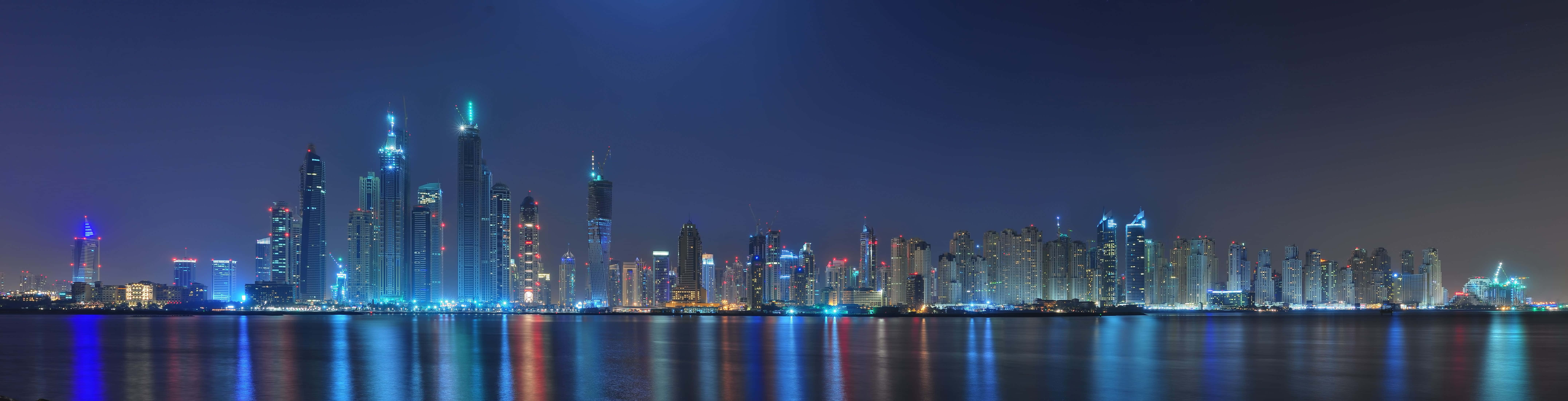 桌布 壁紙 — 杜拜天際線在黑暗天空下平靜水面上反射的耀眼夜景。