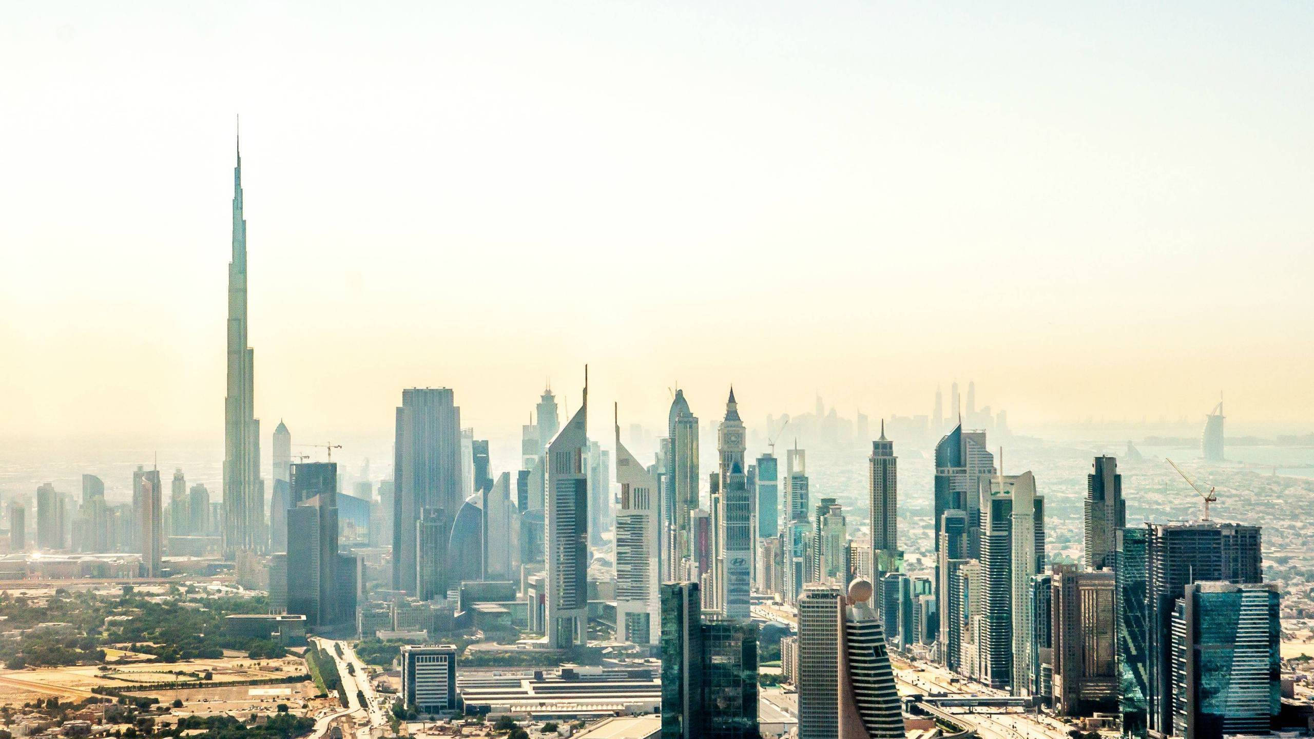Skyscraper 桌布 壁紙 — 杜拜天際線的 panoramatic 景觀，日出時哈里發塔聳立於現代玻璃摩天大樓和朦朧金色光芒之上。