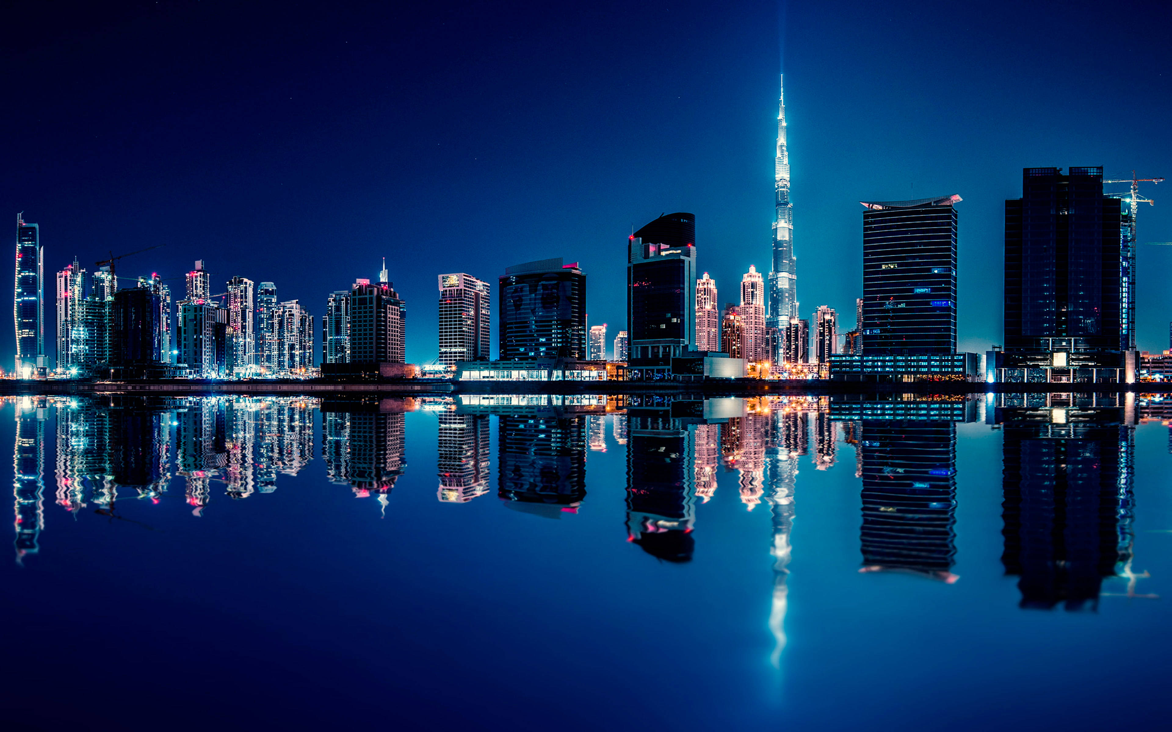 城市 桌布 壁紙 — 杜拜天際線的壯麗夜景，哈里發塔在深藍色天空下聳立於倒映的水面上。