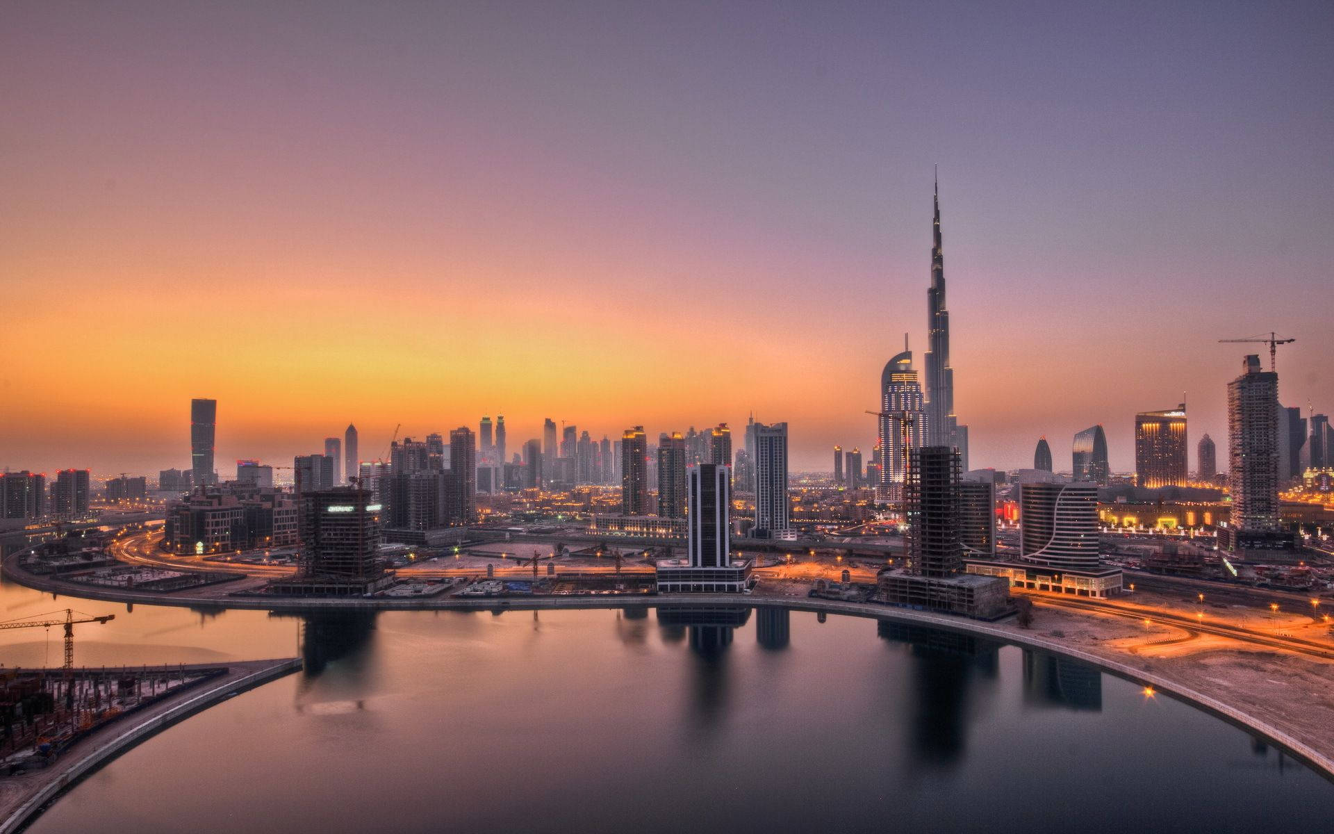桌布 壁紙 — 杜拜天際線的壯麗日落，哈里發塔聳立於現代摩天大樓之上，倒映在平靜的水面上。