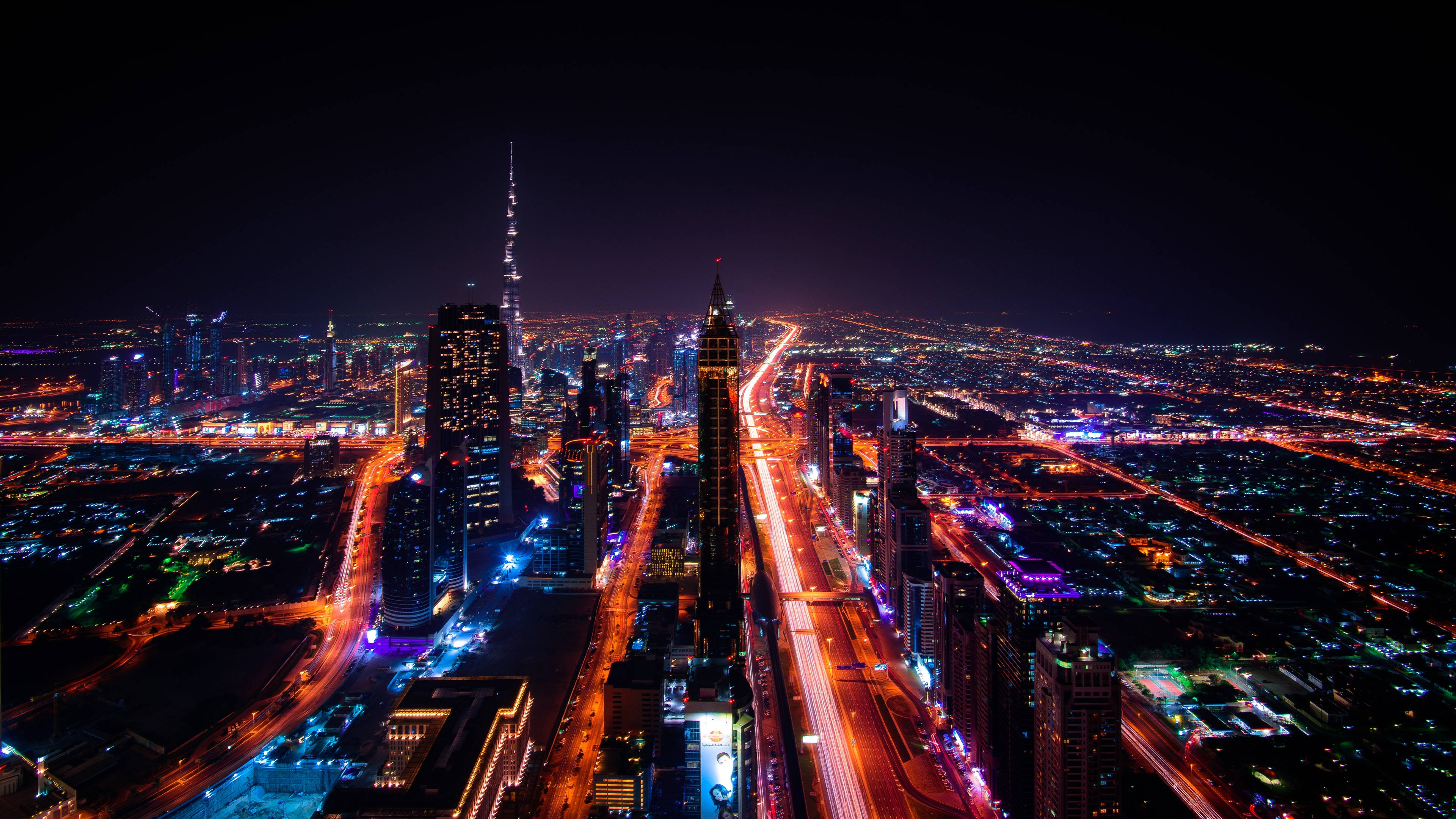 杜拜 桌布 壁紙 — 杜拜天際線的夜間空中景觀，哈里發塔在霓虹燈照亮的道路和摩天大樓中閃耀。