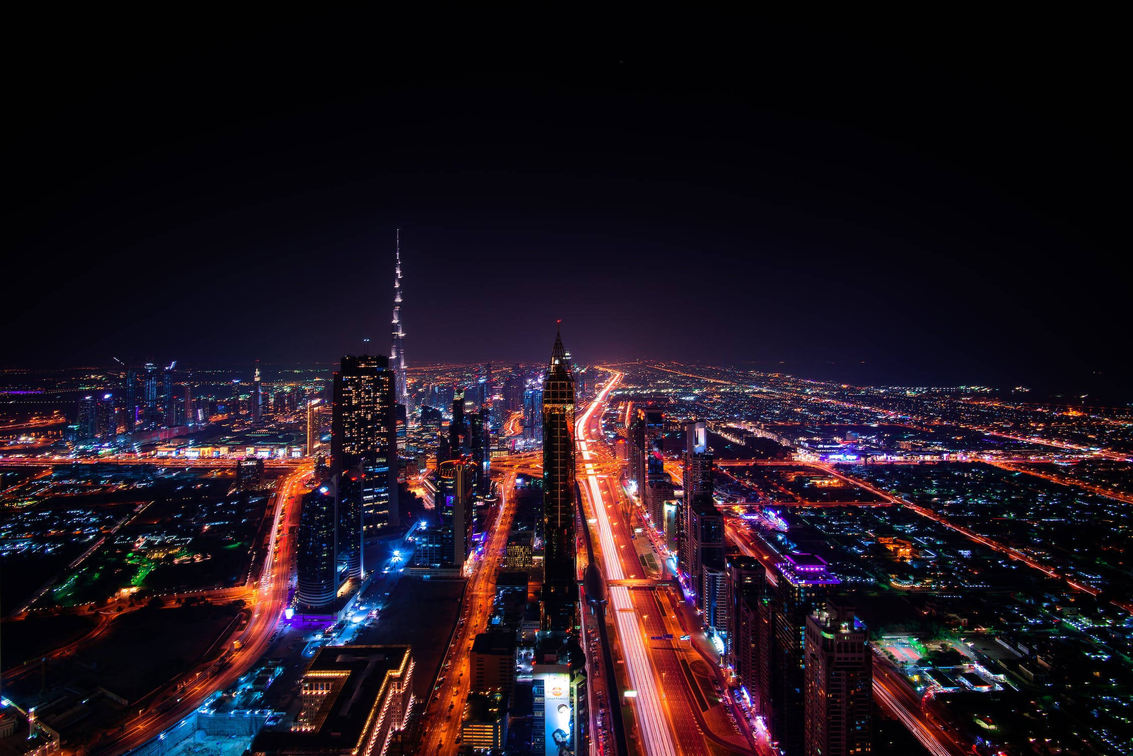 城市 桌布 壁紙 — 杜拜天際線的夜間航拍景觀，哈里發塔在充滿活力的城市燈光和流動的車流中閃耀。