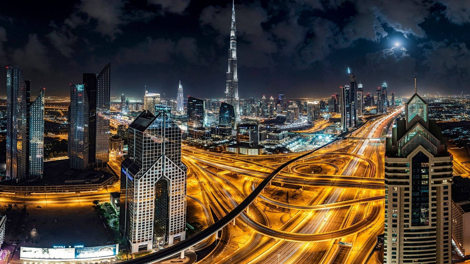Dubai 桌布 壁紙 — 杜拜天際線的夜間航拍景觀，哈里發塔在月光下聳立於發光的高速公路和摩天大樓之上。