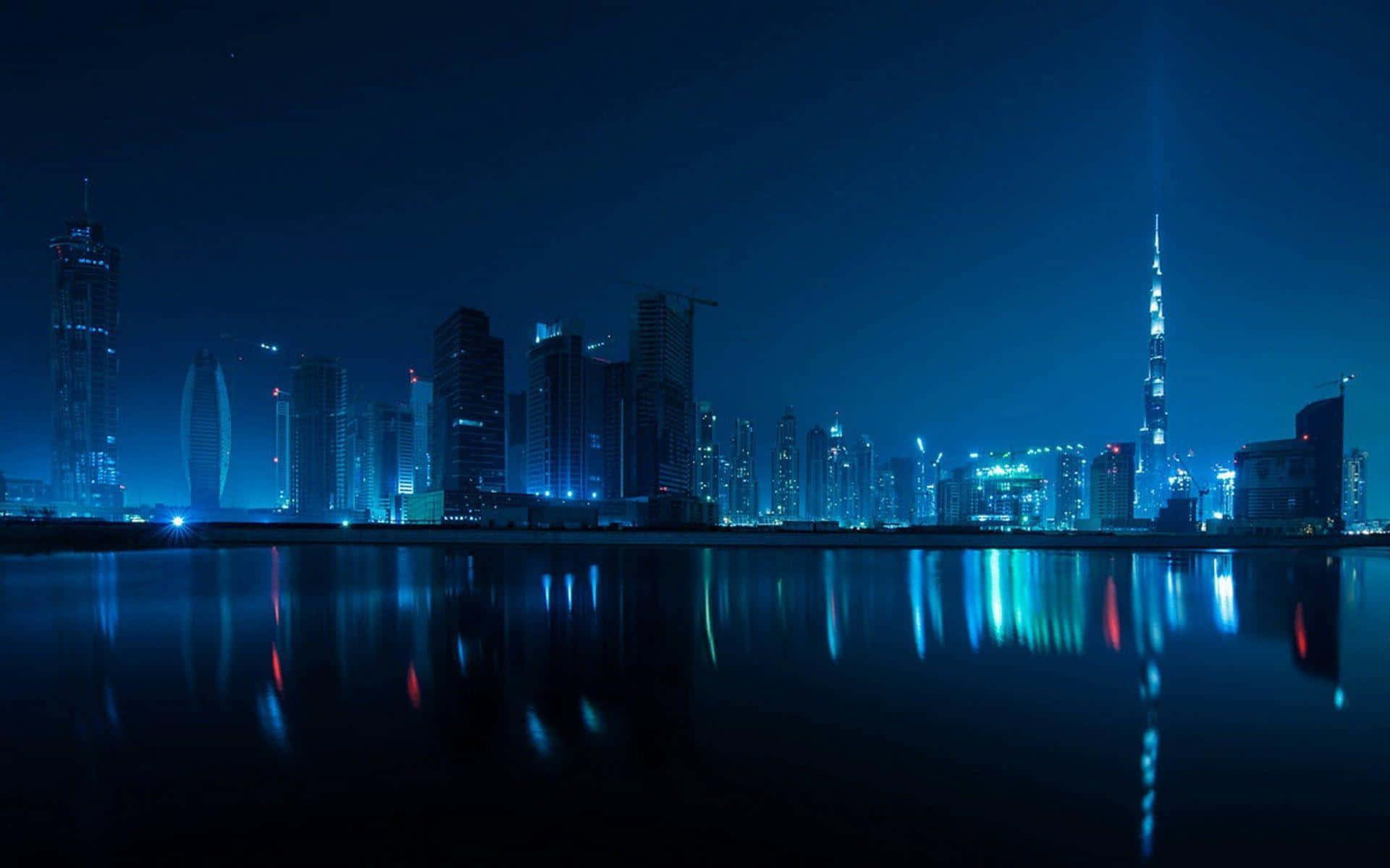 Dubai 桌布 壁紙 — 杜拜天際線的迷人夜景，哈里發塔發出藍色光芒，燈光倒映在平靜的水面上。