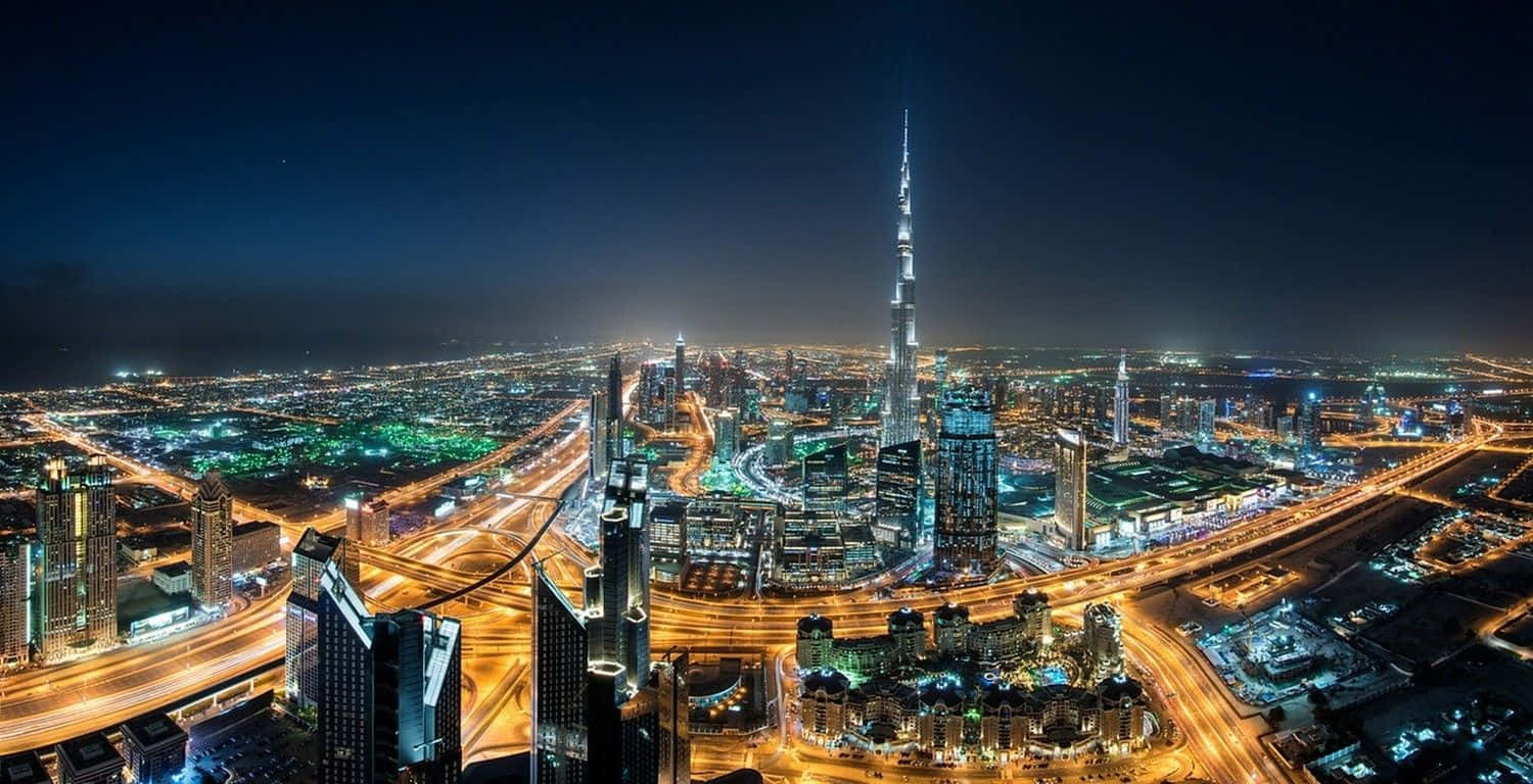 Uae 桌布 壁紙 — 杜拜天際線的迷人夜間鳥瞰圖，以哈里發塔為主導，街道和摩天大樓閃爍著光芒。