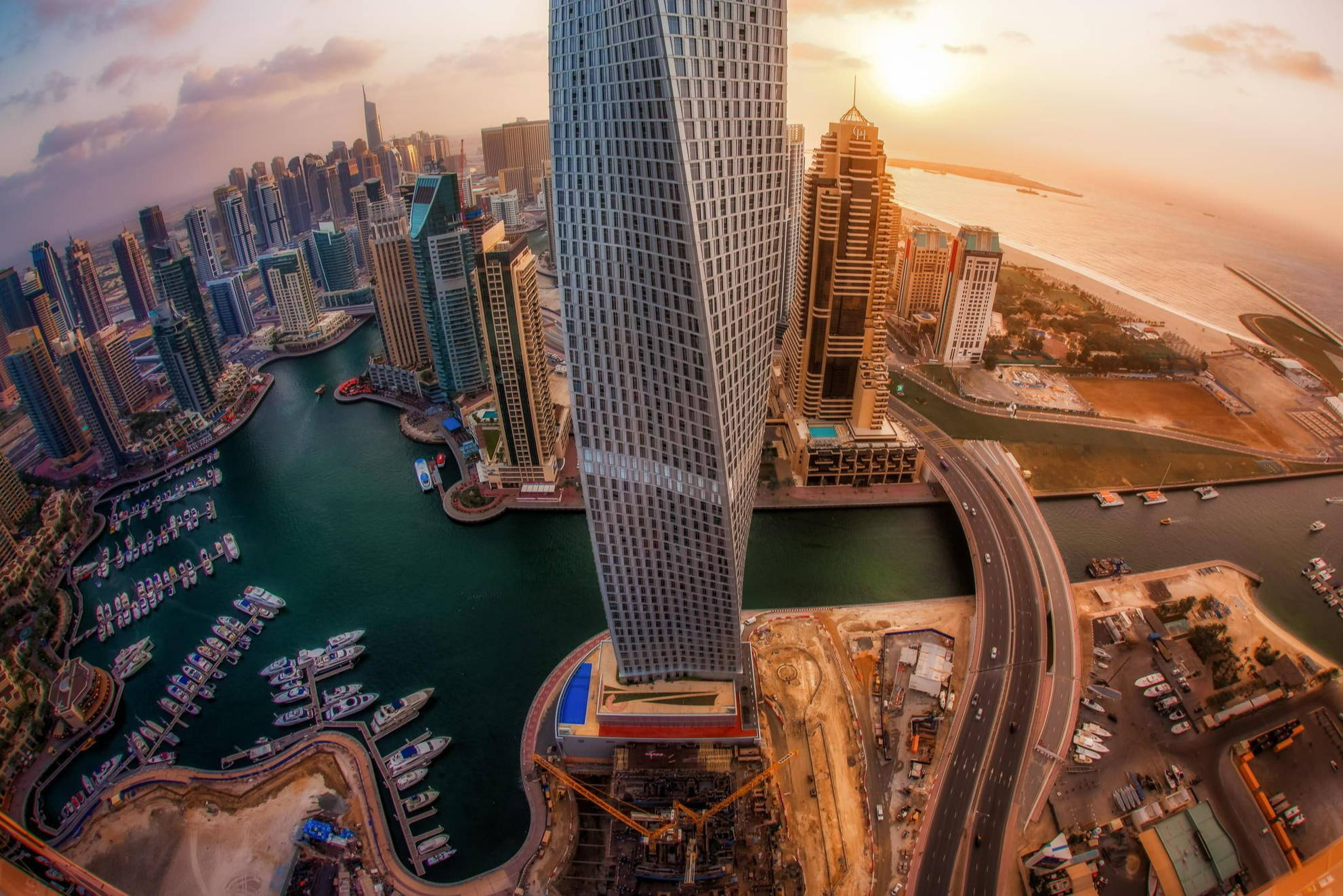 Arab 桌布 壁紙 — 杜拜日落時分的天際線鳥瞰圖，高聳的摩天大樓、碼頭船隻和蜿蜒的高速公路。