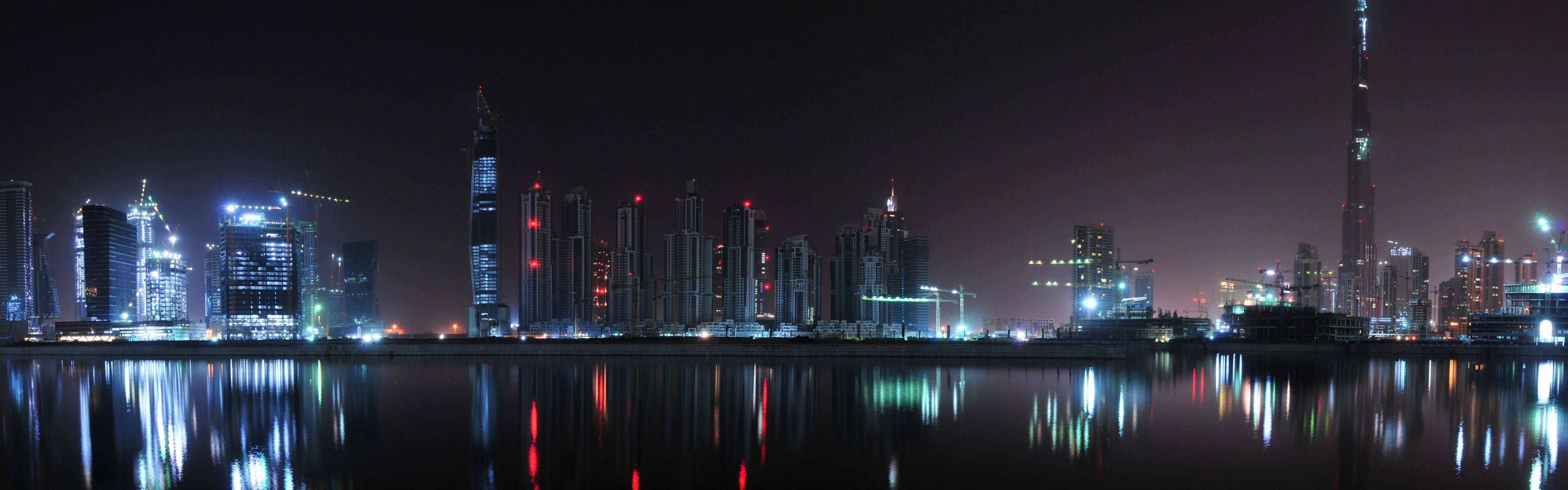 風景 桌布 壁紙 — 杜拜璀璨天際線在平靜水面上倒影的全景夜景，哈里發塔高聳突出。