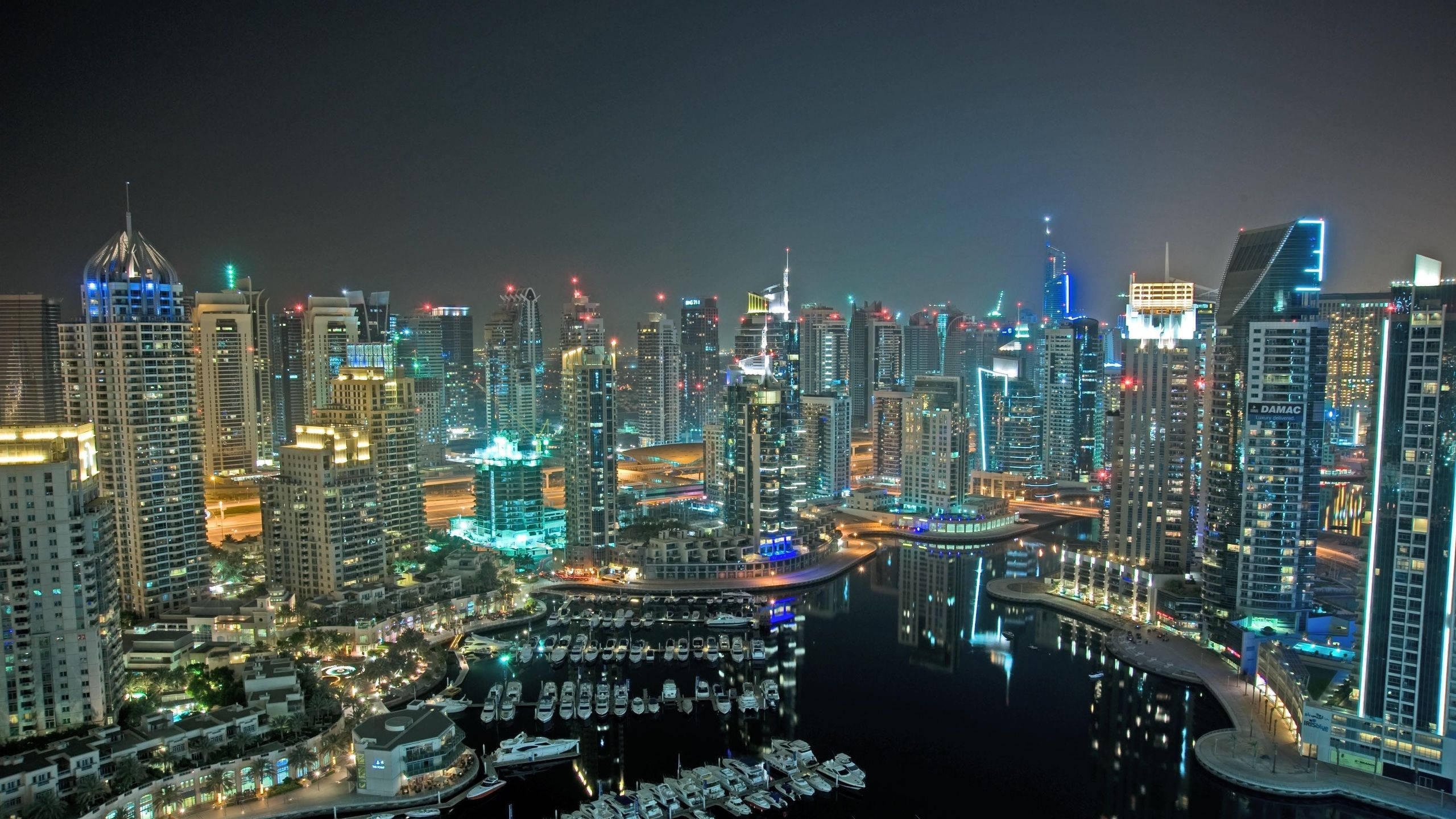Kuwait 桌布 壁紙 — 杜拜碼頭令人目眩神迷的夜景，閃爍的摩天大樓和佈滿遊艇的水面反射著霓虹燈光。
