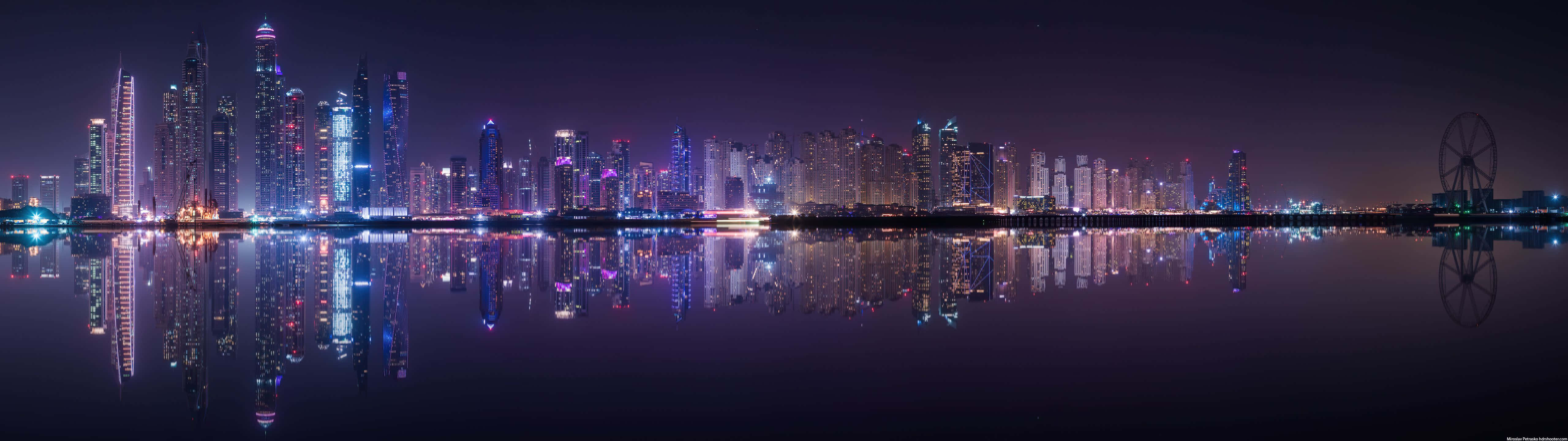 5120x1440 Dual Screen 桌布 壁紙 — 杜拜閃爍天際線的全景夜景，完美倒映在平靜水面上，右邊有一個摩天輪。